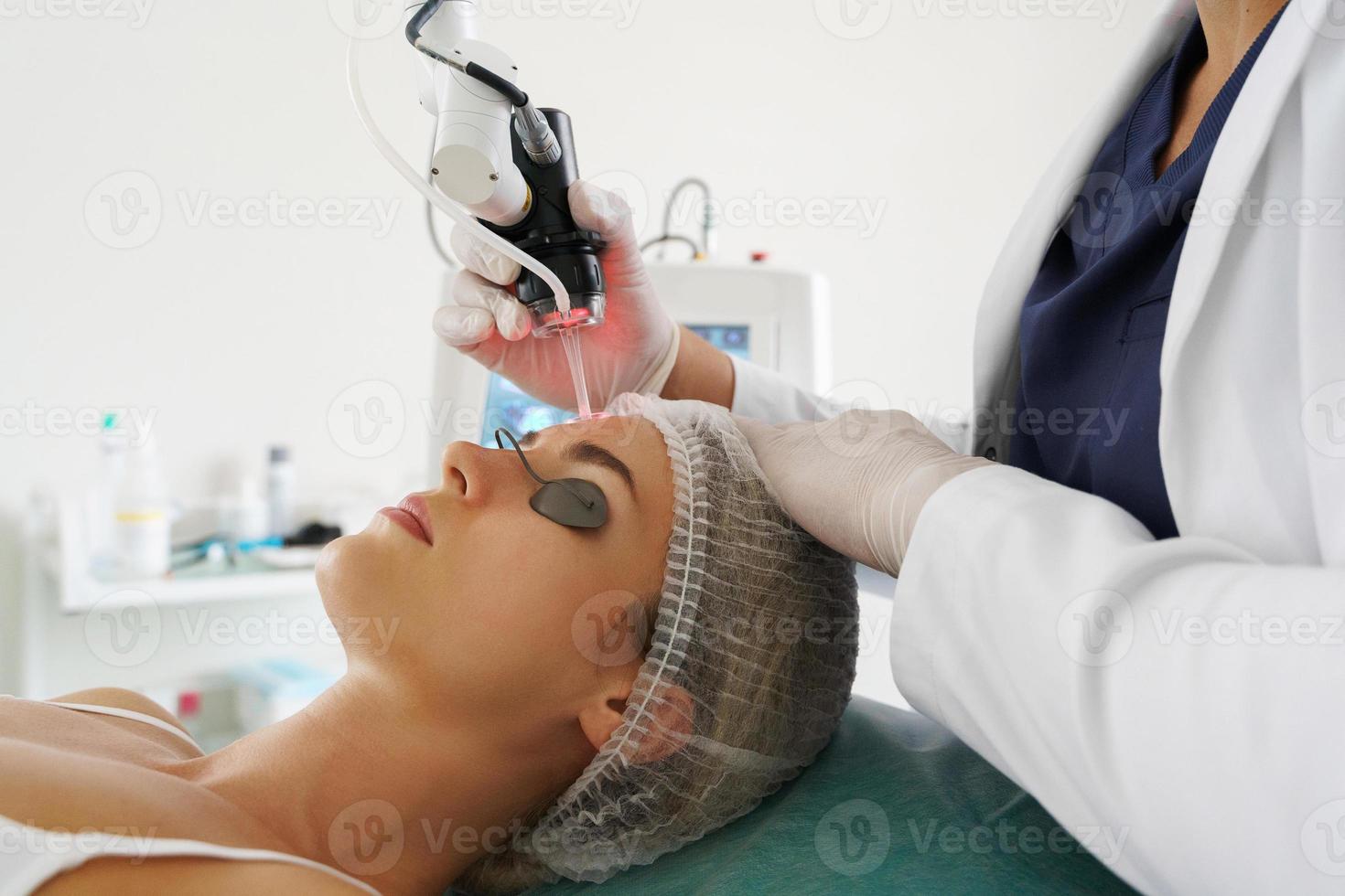 médecin dermatologue et cliente pendant le traitement de resurfaçage de la peau au laser photo