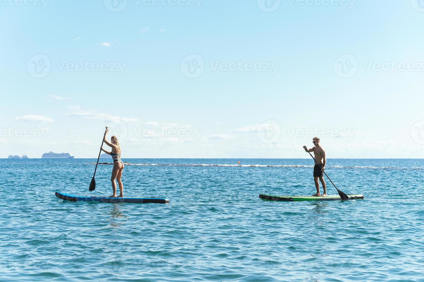 surfeurs masculins et féminins faisant du stand-up paddleboards dans l'océan. photo