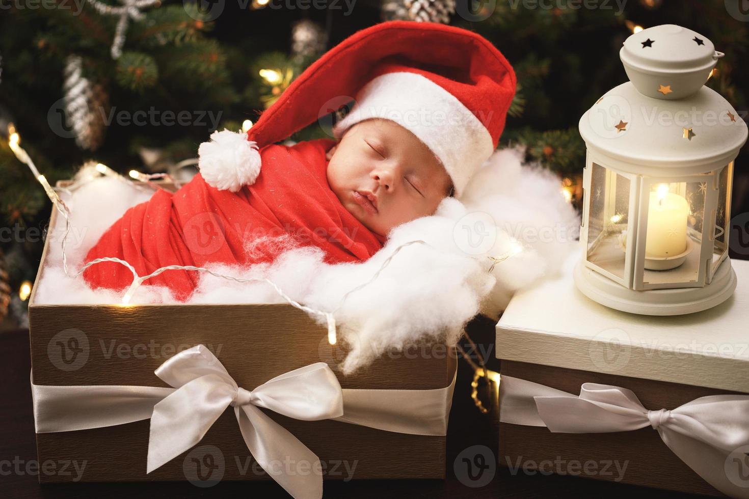 mignon bébé nouveau-né portant un chapeau de père noël dort dans la boîte de cadeau de noël photo