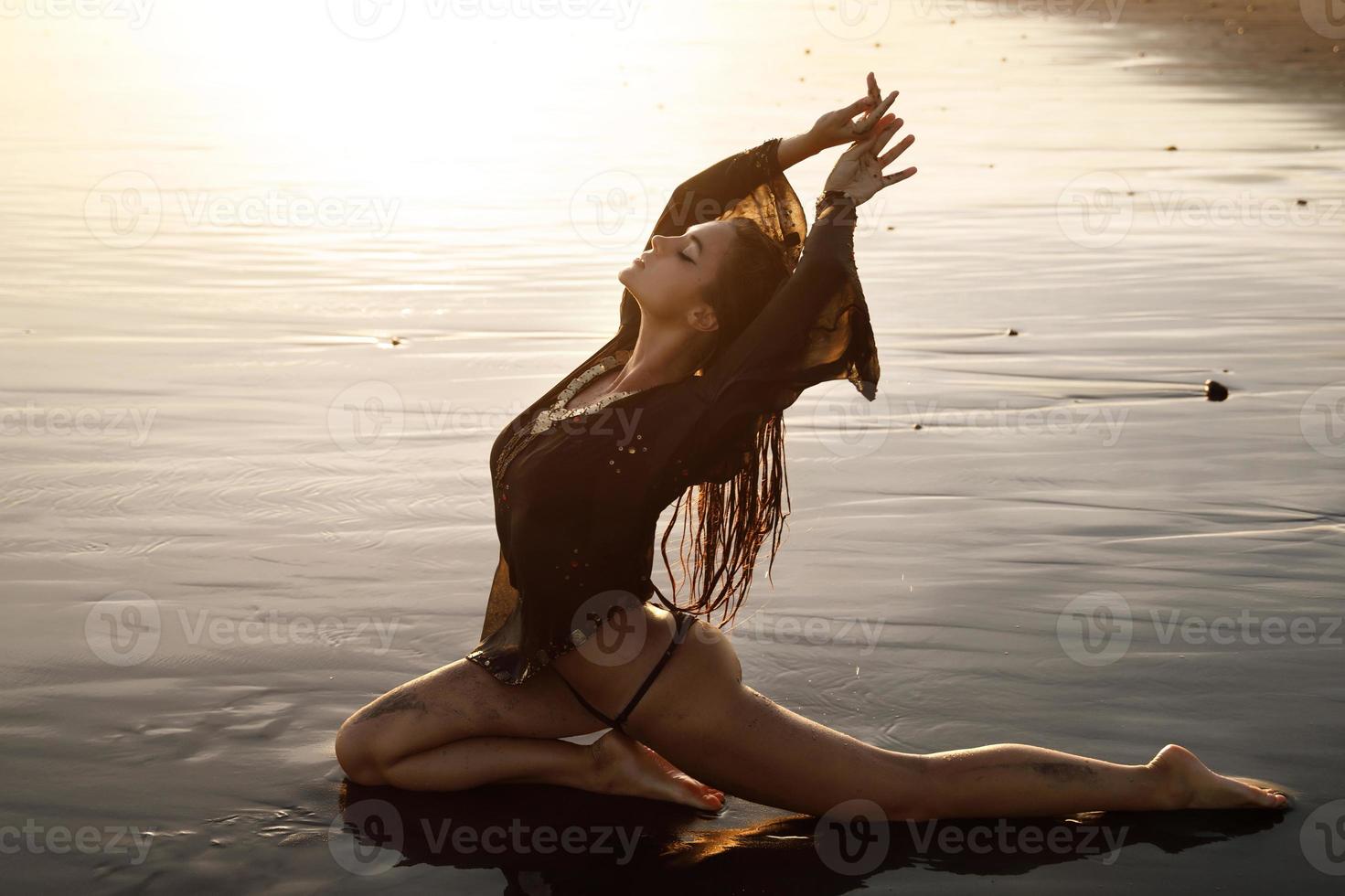 femme sexy portant une tunique noire pose sur la plage avec du sable noir photo