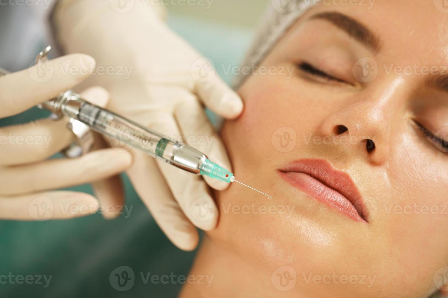 femme recevant une injection d'anesthésique local avant une chirurgie faciale dans une clinique médico-esthétique photo