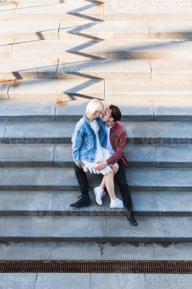 Teenage couple sitting and kissing sur un escalier en béton photo