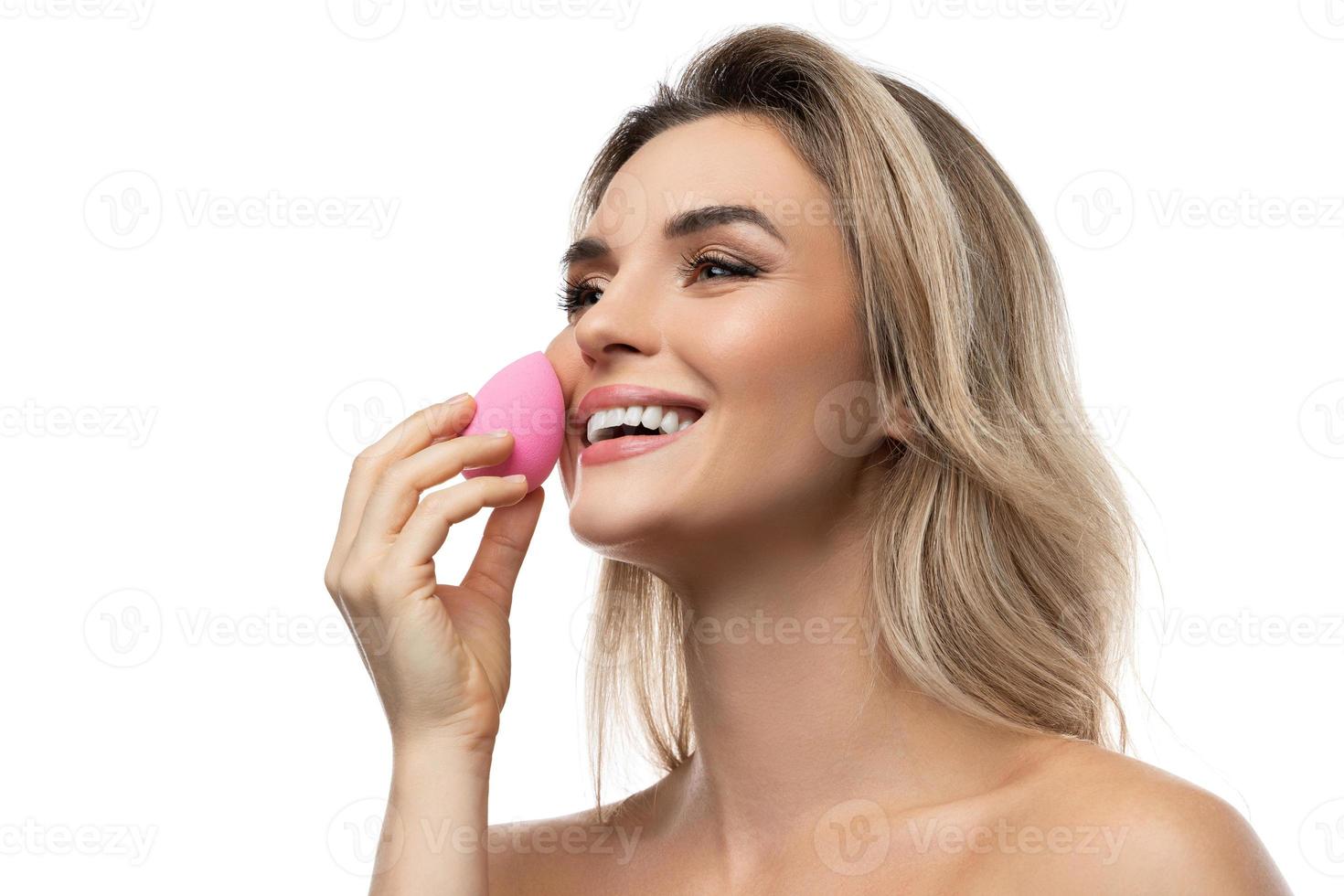 belle femme avec une peau lisse tenant une éponge de maquillage sur fond blanc photo