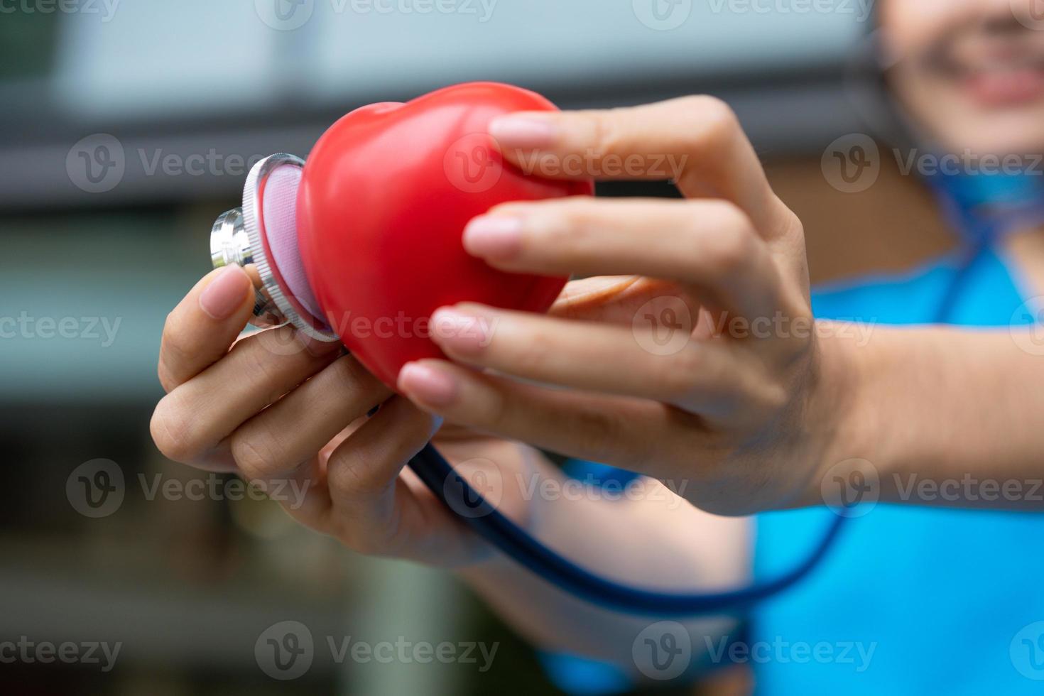 femme médecin de maladies cardiovasculaires ou cardiologue avec stéthoscope tenant coeur rouge, soins de santé médicaux et concept de service de personnel médical. photo