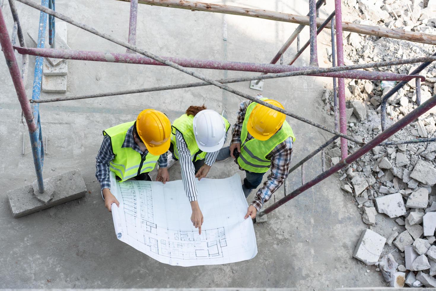 vue de dessus d'un ingénieur asiatique ou d'une jeune architecte féminine met un casque pour la sécurité et parle avec un entrepreneur sur un projet d'usine de construction, concept de travail d'équipe, concept de leadership. photo