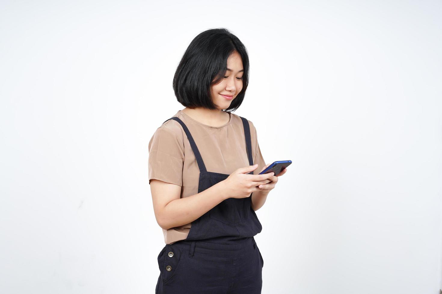 à l'aide d'un smartphone et souriant d'une belle femme asiatique isolée sur fond blanc photo