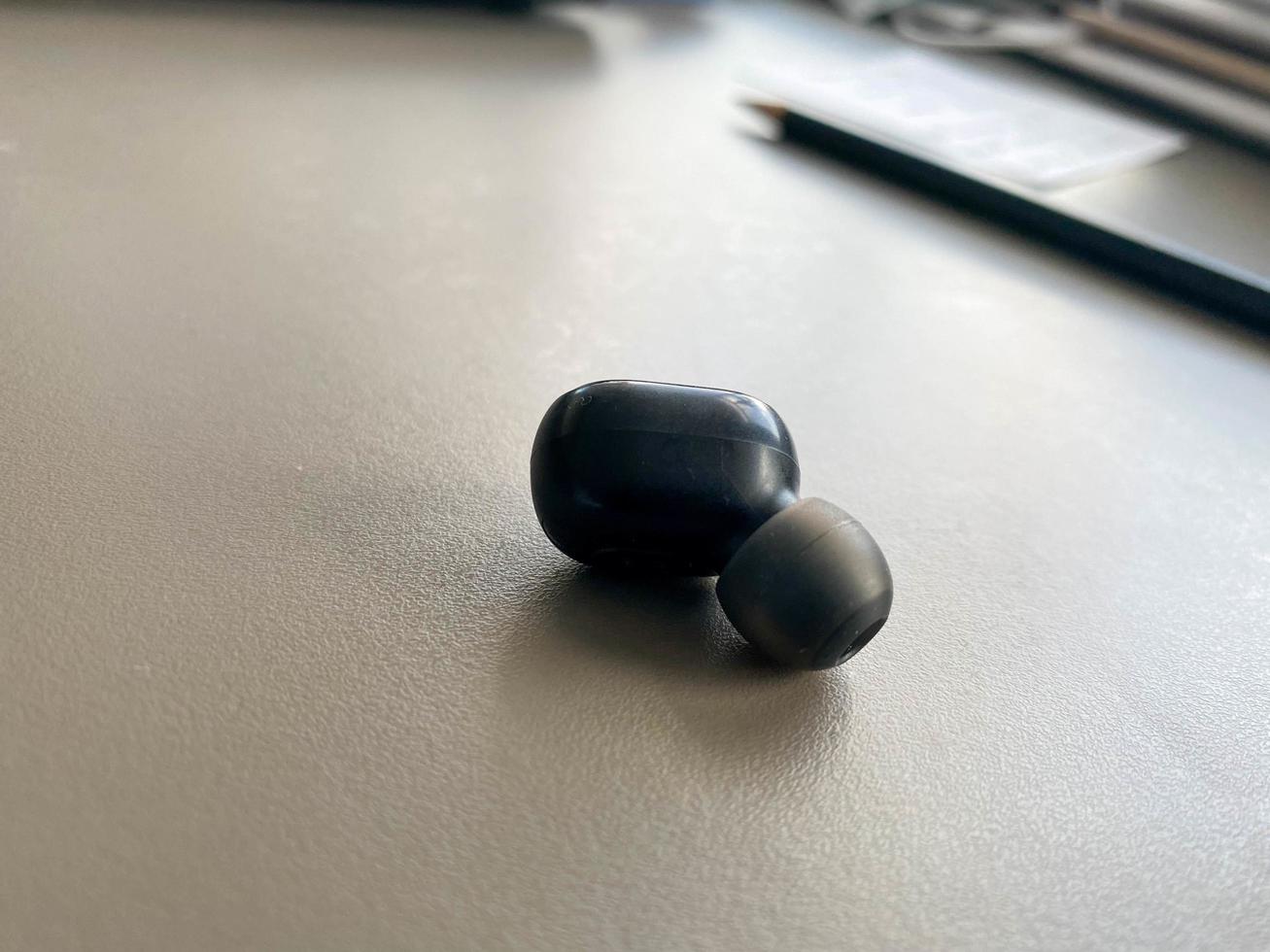 un petit écouteur bluetooth sans fil en plastique noir pour écouter de la musique se trouve sur la table photo