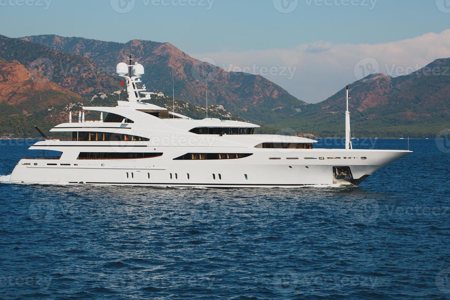 beau yacht blanc moderne avec voile sur la mer bleue, sur fond de montagnes. photo