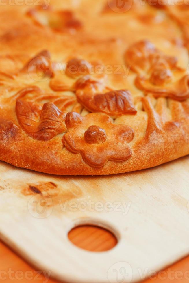 tarte russe aux pommes de terre et champignons sur la table. gros gâteau fraîchement cuit décoré de fleurs de leur pâte photo