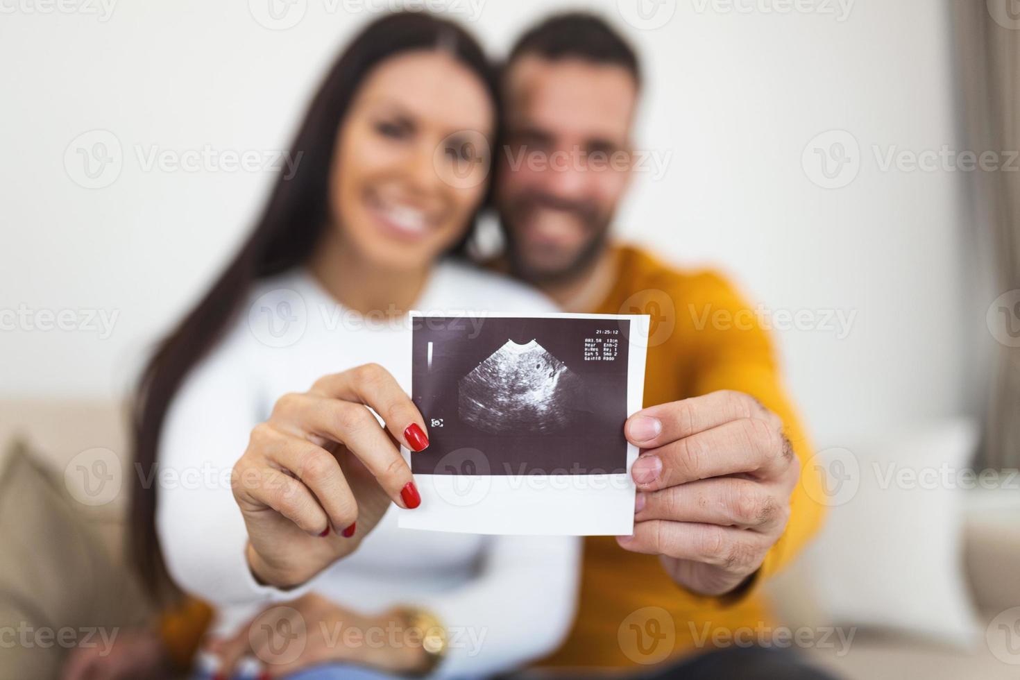 femme et son petit ami brandissant une image de son échographie du bébé. jeune couple heureux avec bébé photo échographique