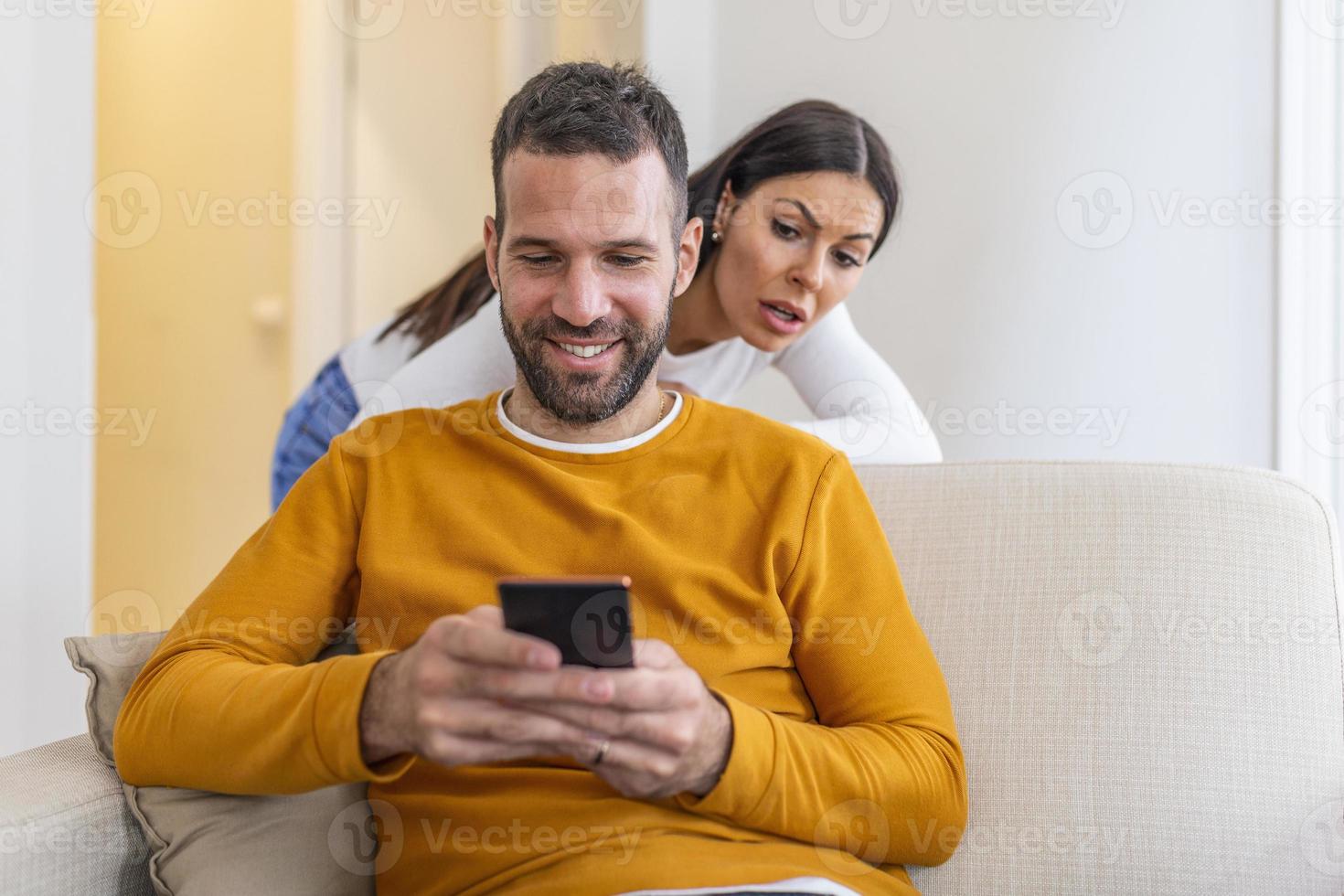 petite amie jalouse essaie de jeter un coup d'œil sur le téléphone intelligent de son petit ami, se sent triste alors qu'il envoie des SMS à quelqu'un, vêtu de chandails décontractés, a des problèmes avec les relations. photo