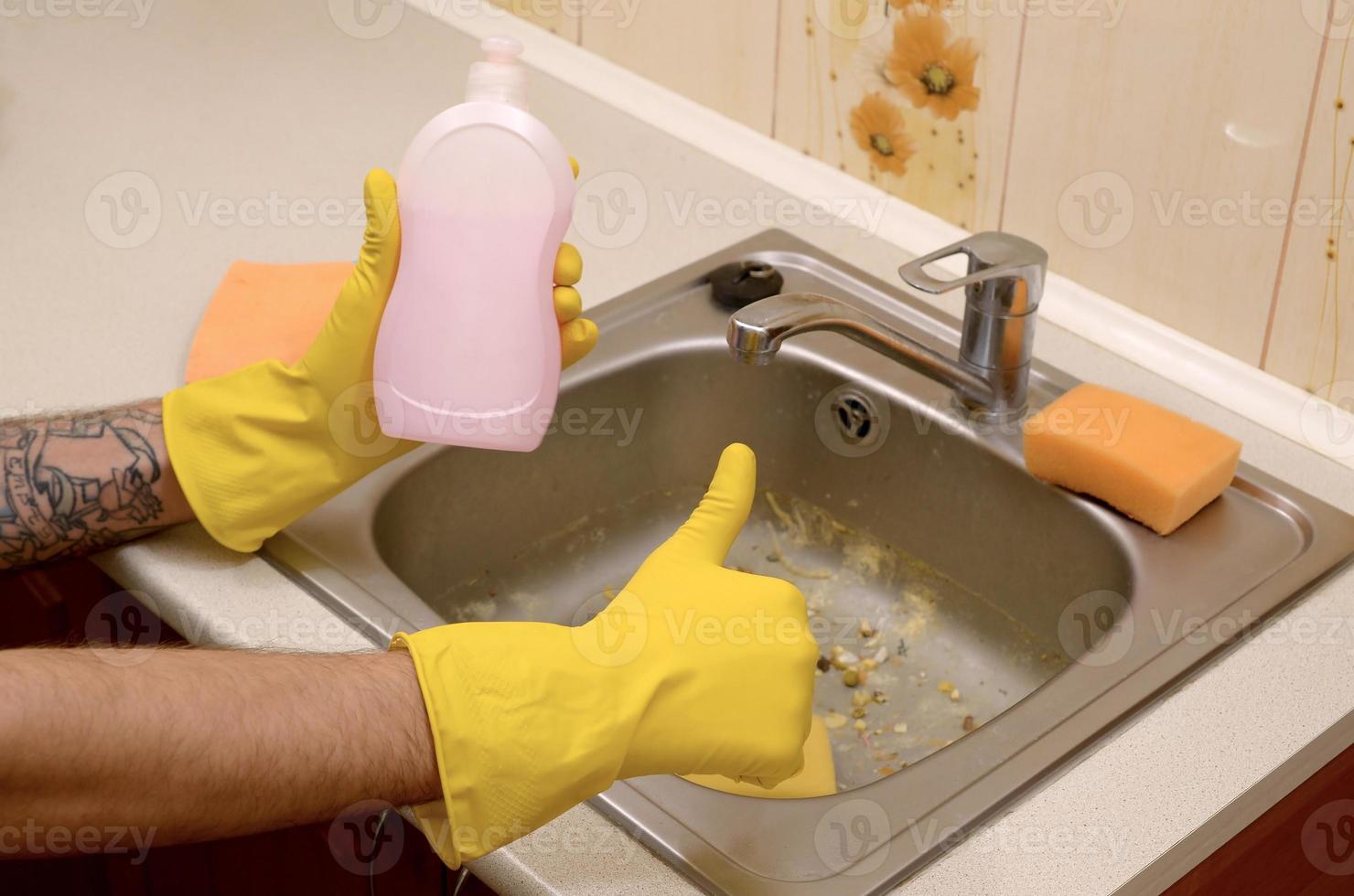 le nettoyant montre une bouteille de détergent liquide dans un évier de cuisine sale avec des particules de nourriture avant le nettoyage photo