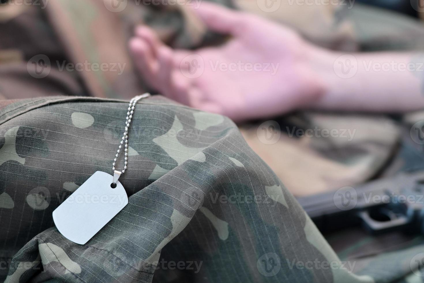 un jeton vide de l'armée d'un soldat militaire mort repose sur des vêtements de camouflage photo