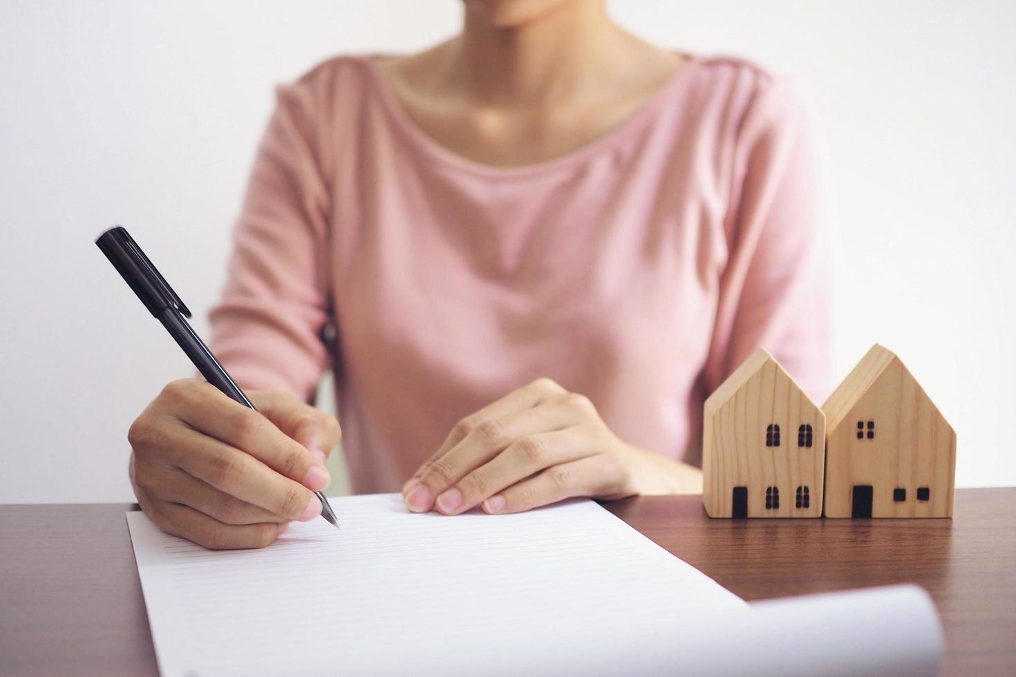 des maisons modèles avec des agents immobiliers discutent d'un contrat d'achat d'une maison, d'un bail, d'une assurance ou d'un prêt immobilier. notion d'entreprise. photo