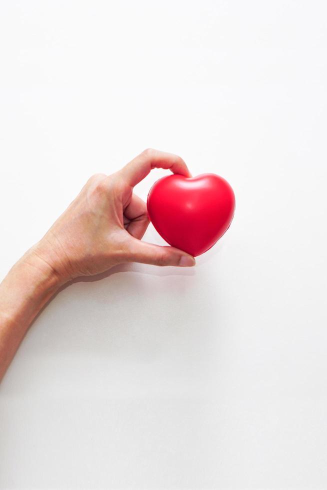 main de femme tenant un coeur rouge sur fond blanc. concept de soins, de santé, d'assurance et de journée d'amour. photo