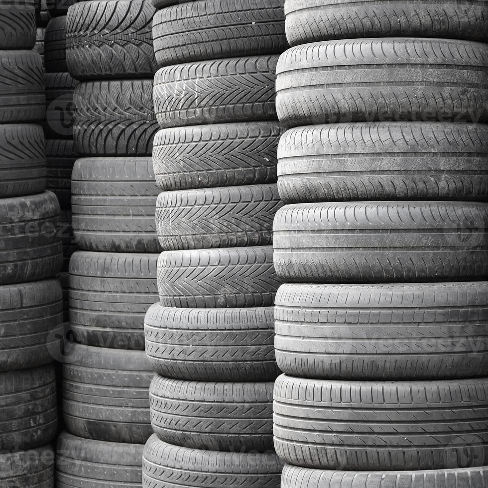 Vieux pneus usagés empilés avec des pieux élevés dans le garage de l'atelier de pièces de voiture secondaire photo
