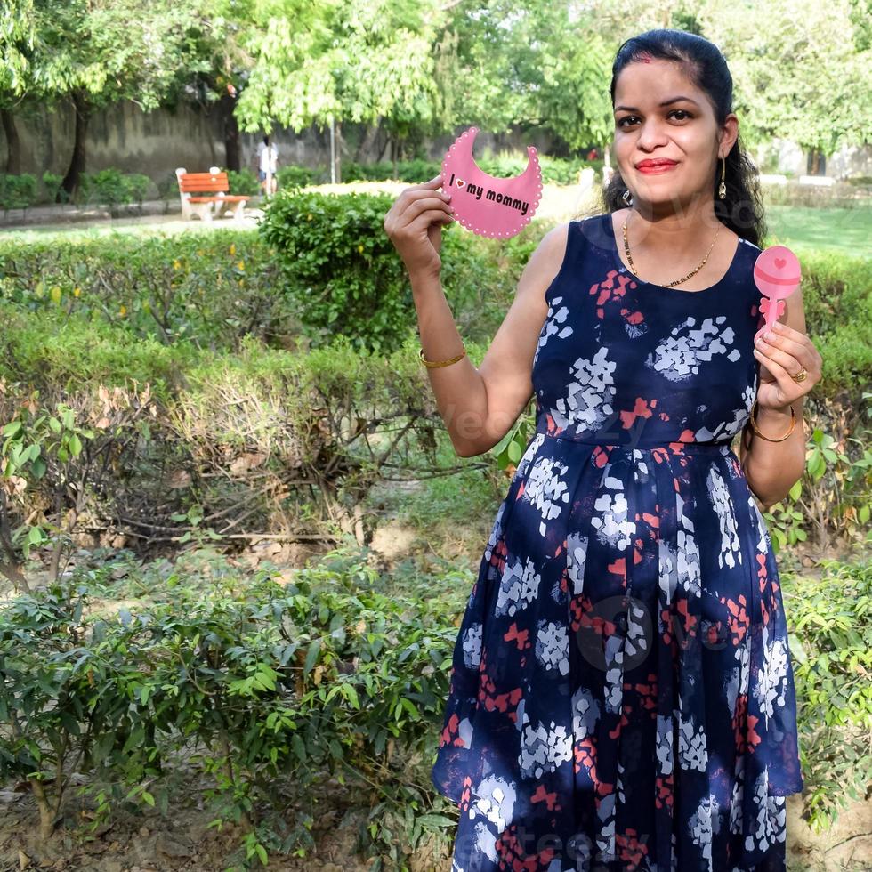 couple indien posant pour une séance photo de maternité. le couple pose dans une pelouse avec de l'herbe verte et la femme étale sa bosse de bébé dans le jardin de lodhi à new delhi, inde