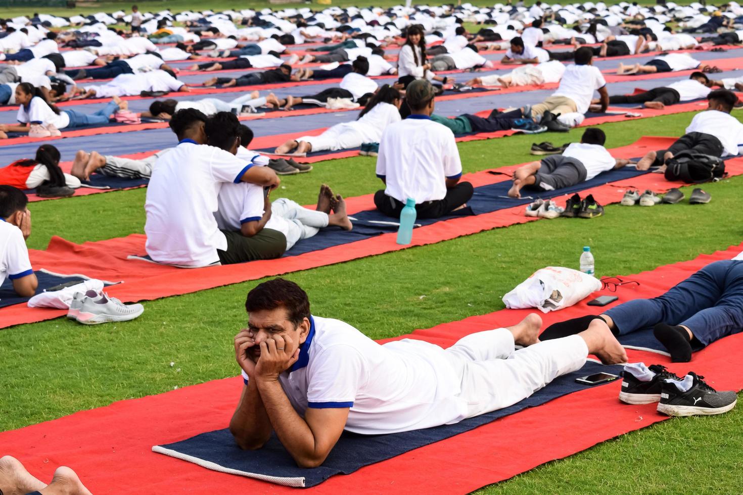 new delhi, inde, 21 juin 2022 - séance d'exercices de yoga en groupe pour les personnes du complexe sportif de yamuna à delhi lors de la journée internationale du yoga, grand groupe d'adultes assistant à un cours de yoga au stade de cricket photo