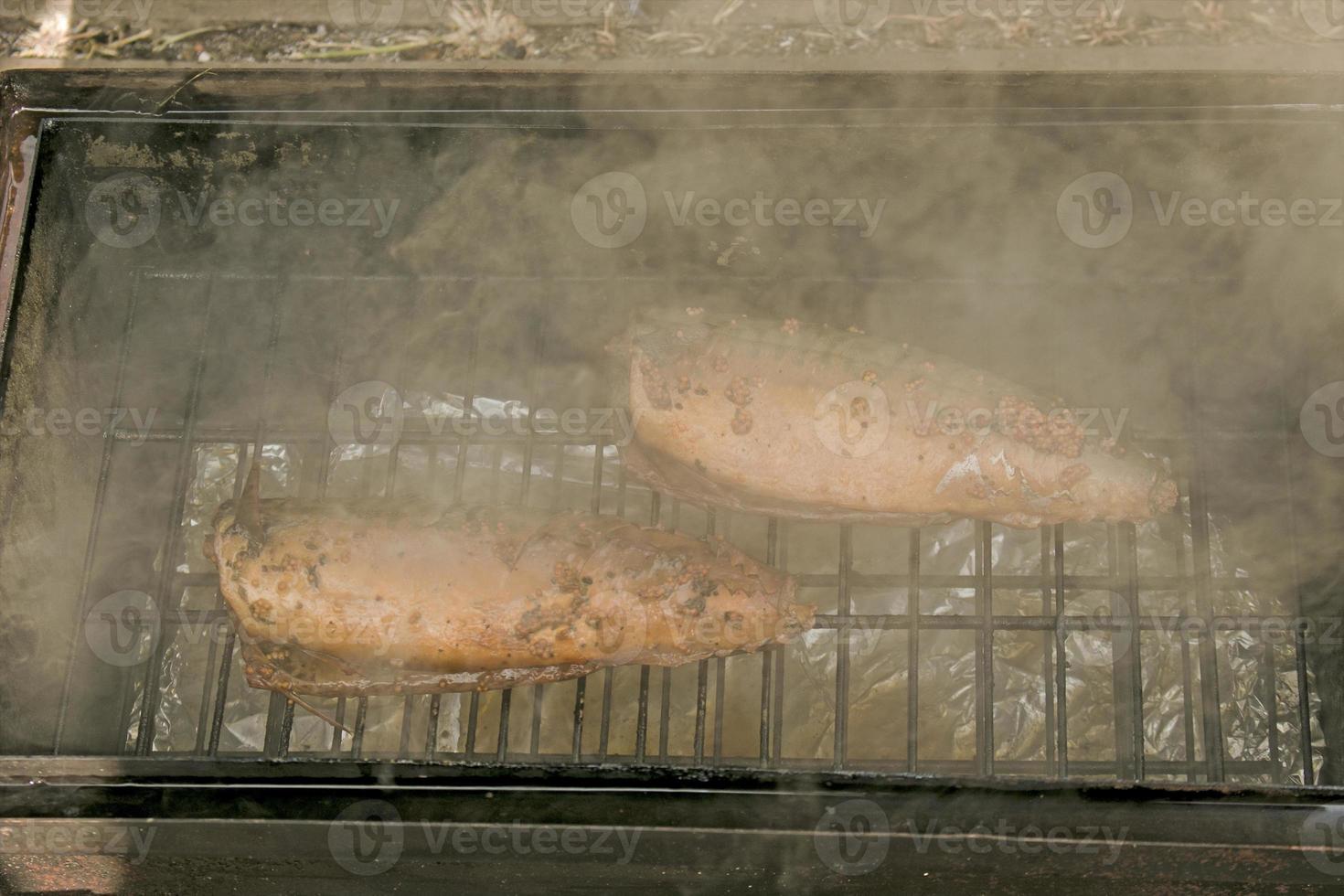 poisson maquereau dans une marinade sur un gril dans un fumoir. le processus de cuisson du maquereau fumé à chaud photo