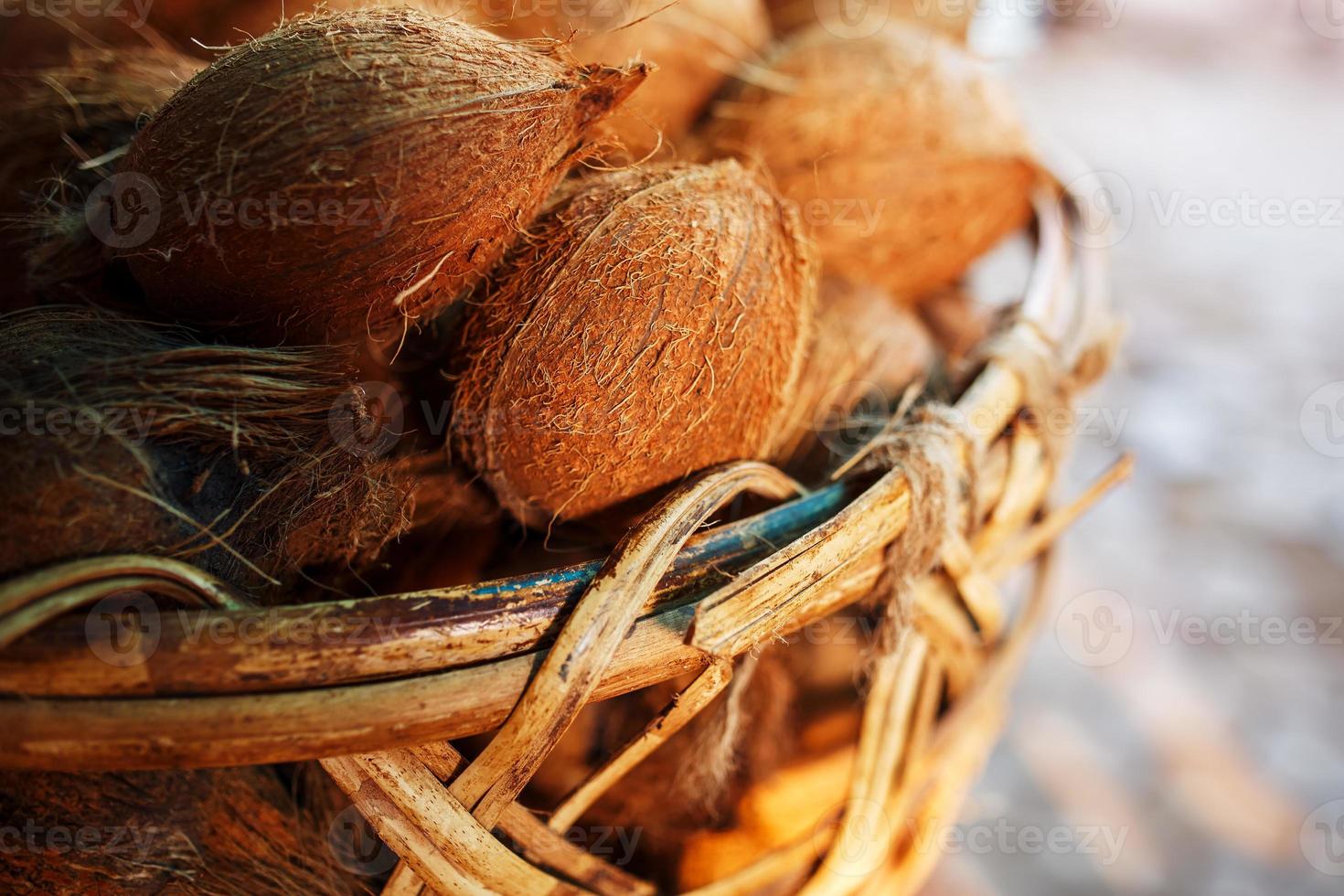 noix de coco dans un panier en osier de couleur marron avec des fibres éclairées par la lumière du soleil. pile sur le marché photo