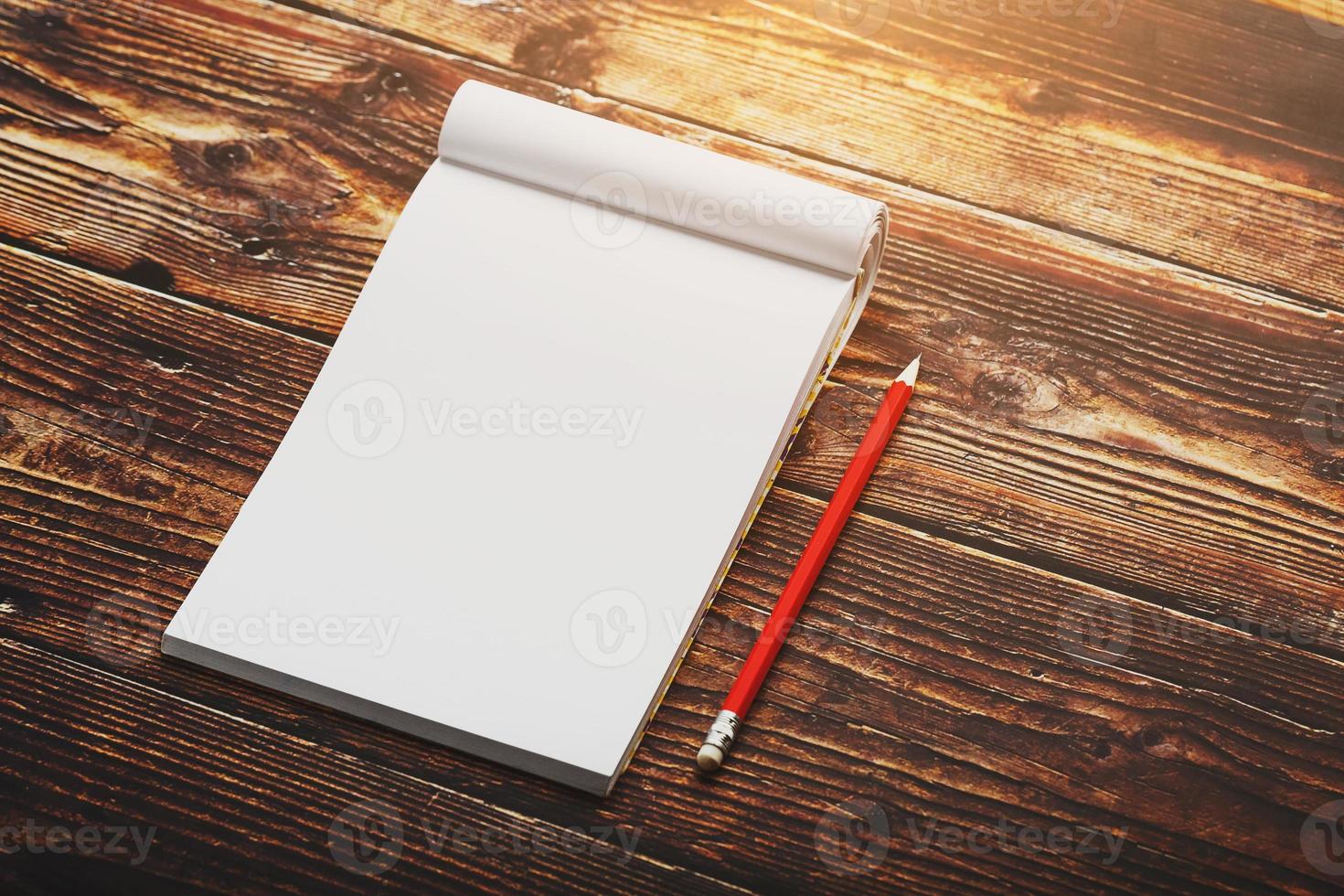 cahier avec un crayon rouge sur fond marron avec lumière du soleil chaude, pour l'écriture. espace vide libre pour écrire sur une feuille vierge d'un cahier. photo