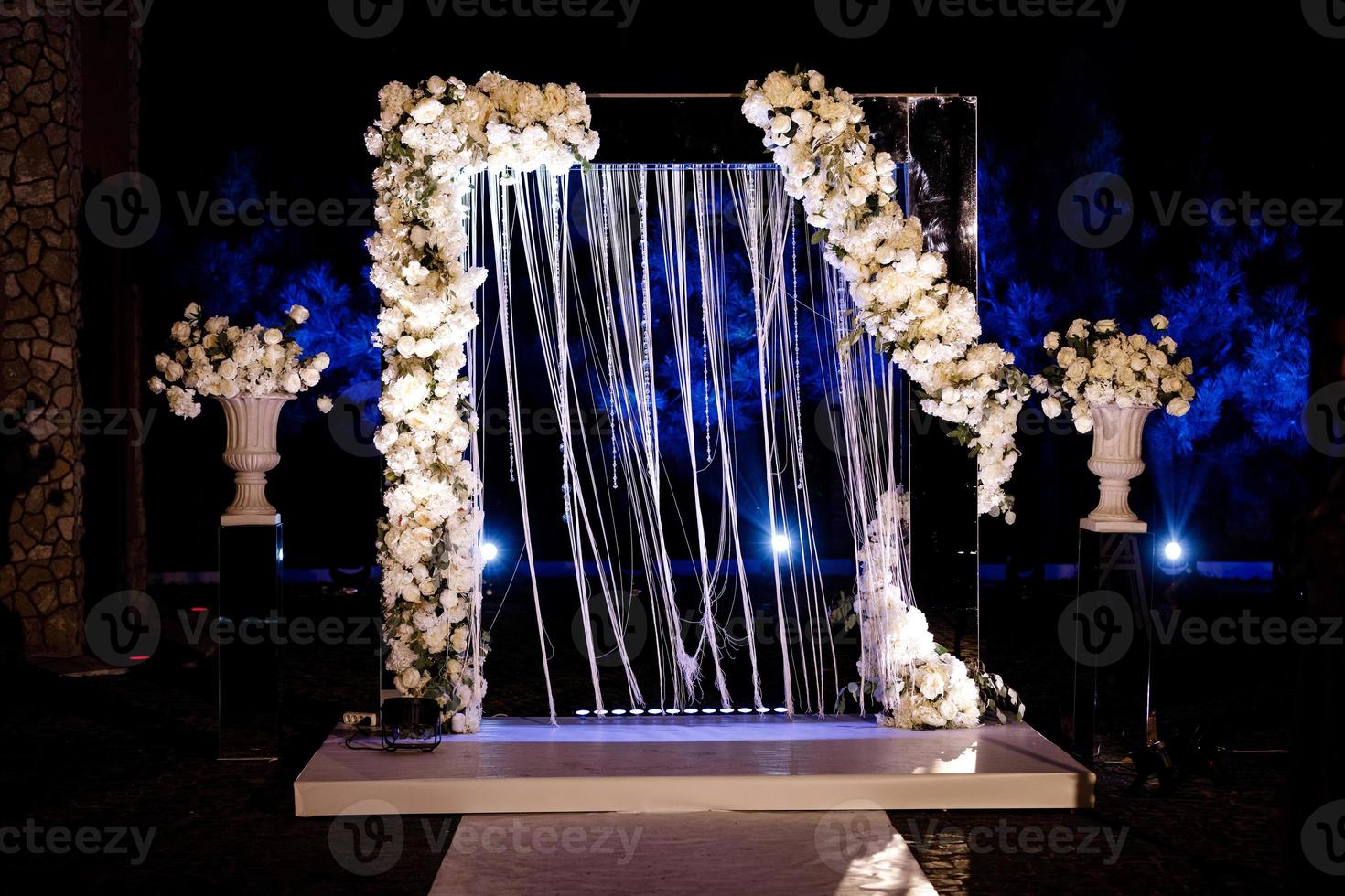 cérémonie de mariage nocturne, arche sur fête décorée de fleurs blanches et de lumières en plein air. décoration d'arc de mariage. bouquet. photo