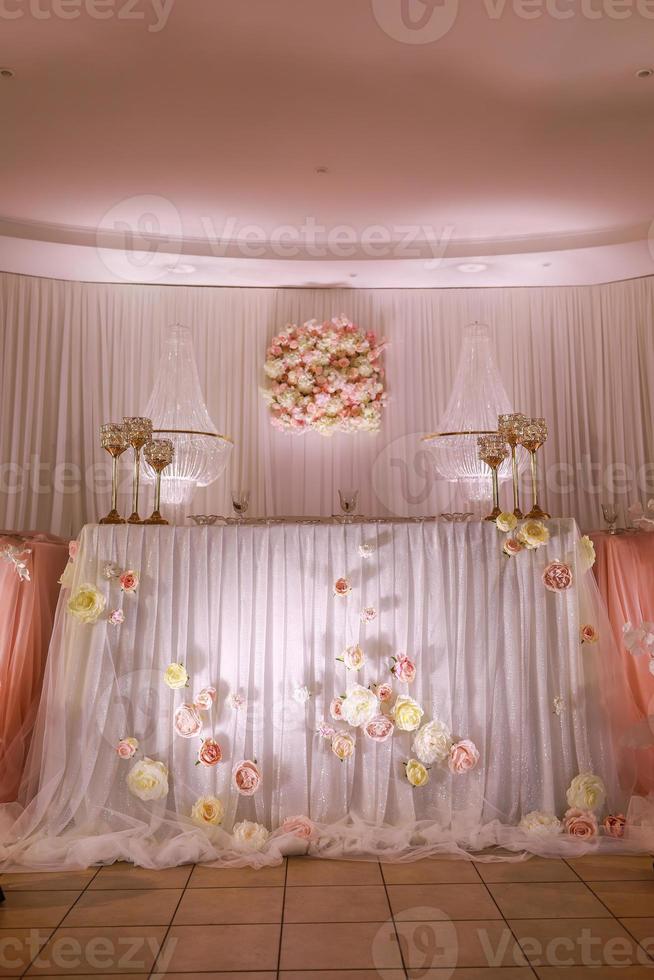 décoration de table de mariage festive avec lustres en cristal, chandeliers dorés, bougies et fleurs roses blanches. jour de mariage élégant photo