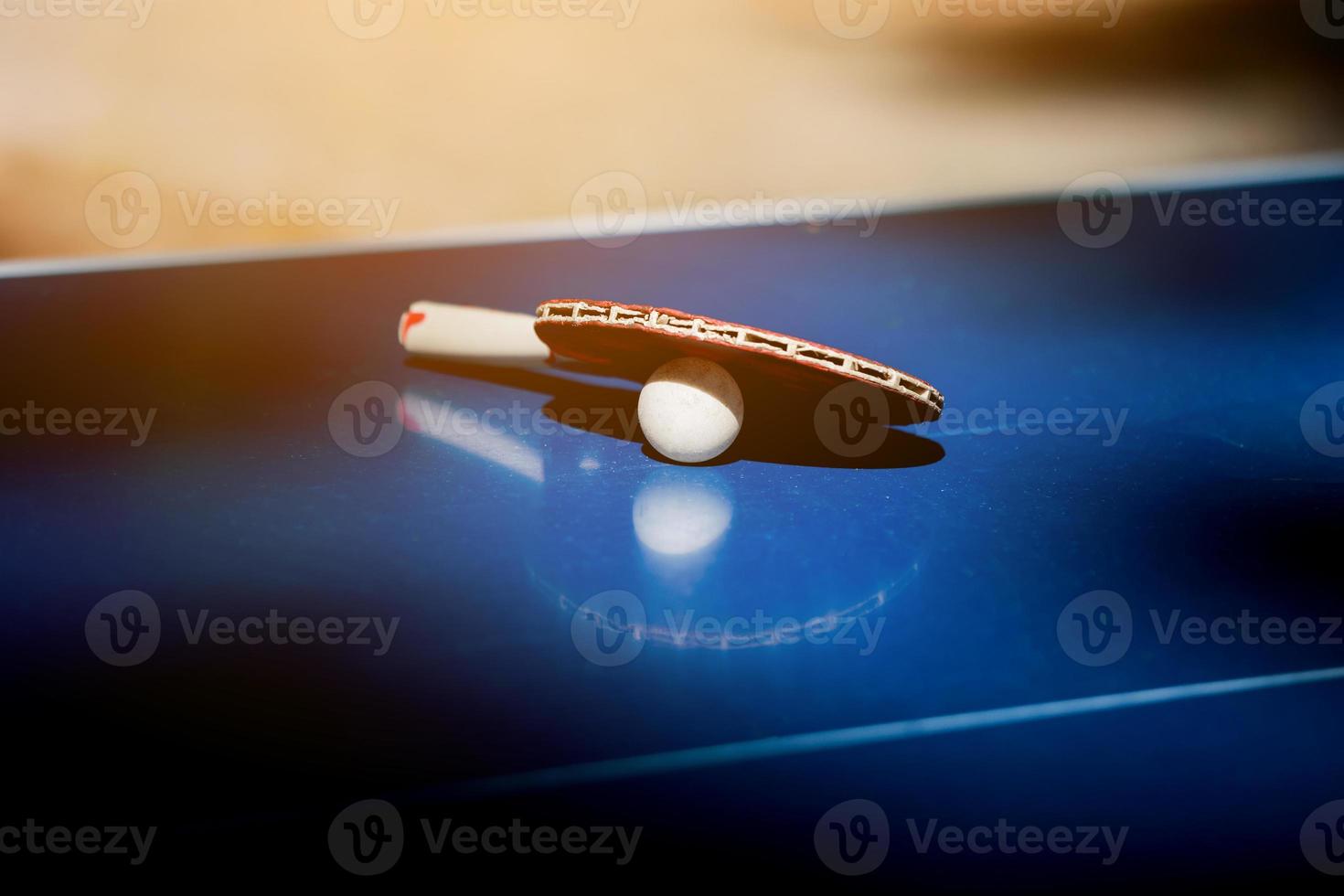 raquette en bois pour ping-pong et balle blanche posée sur la table bleue. matériel de raquettes de tennis de table. passe-temps, activité photo