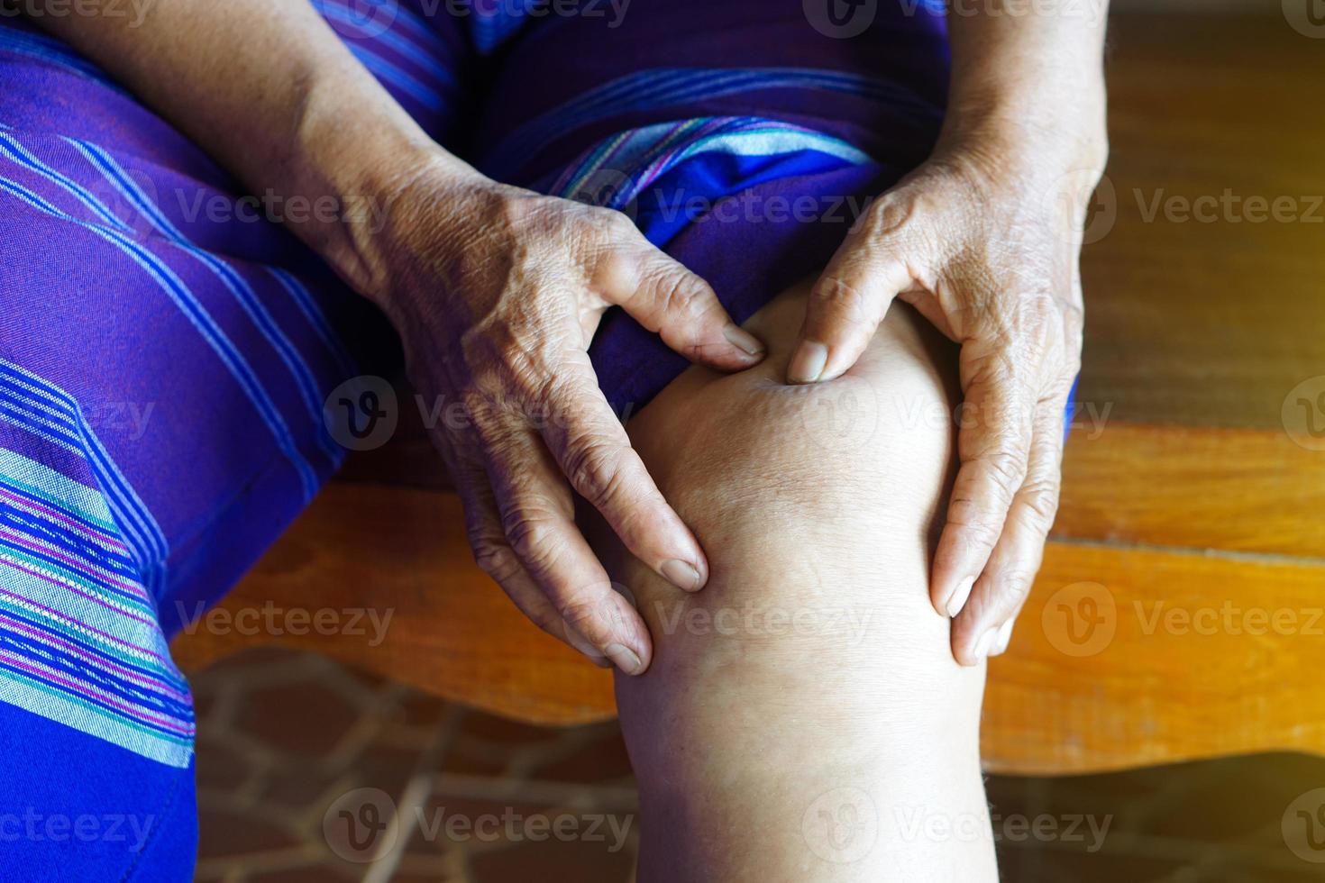 gros plan les mains d'une femme âgée massent son genou douloureux. concept, problèmes de santé. blessure au genou, arthrose. os superposé. photo