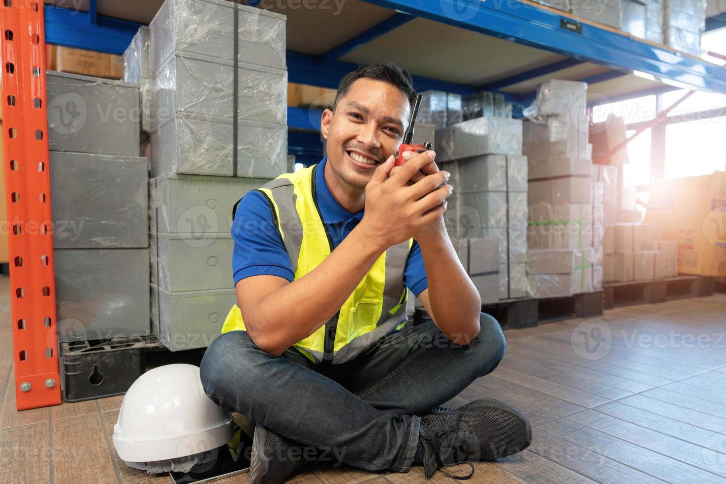 travailleur masculin asiatique en uniforme de sécurité parlant au talkie-walkie à des collègues. ingénieur ou chauffeur travaillant au centre de distribution de l'entrepôt logistique. Expédition et livraison photo