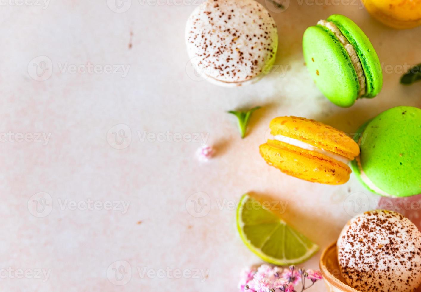 macarons français ou italiens colorés au citron vert, à la menthe et aux fleurs, fond de béton clair. fond de nourriture sucrée. photo