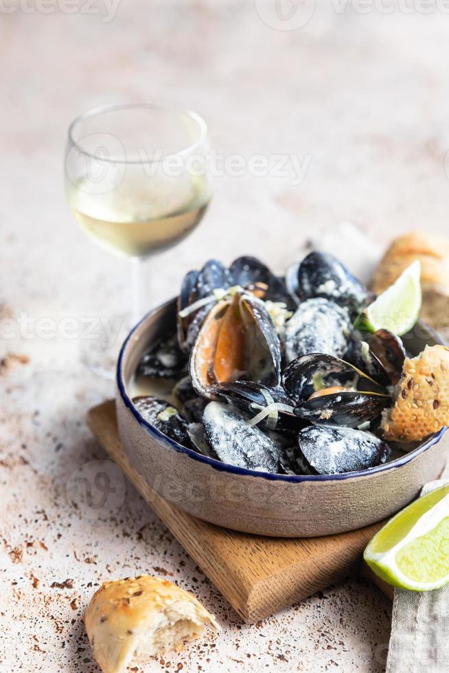 moules bleues dans une sauce crémeuse au vin blanc servies avec citron vert et pain. moules mijotées au vin, poireaux et fromage bleu. Fruit de mer. photo