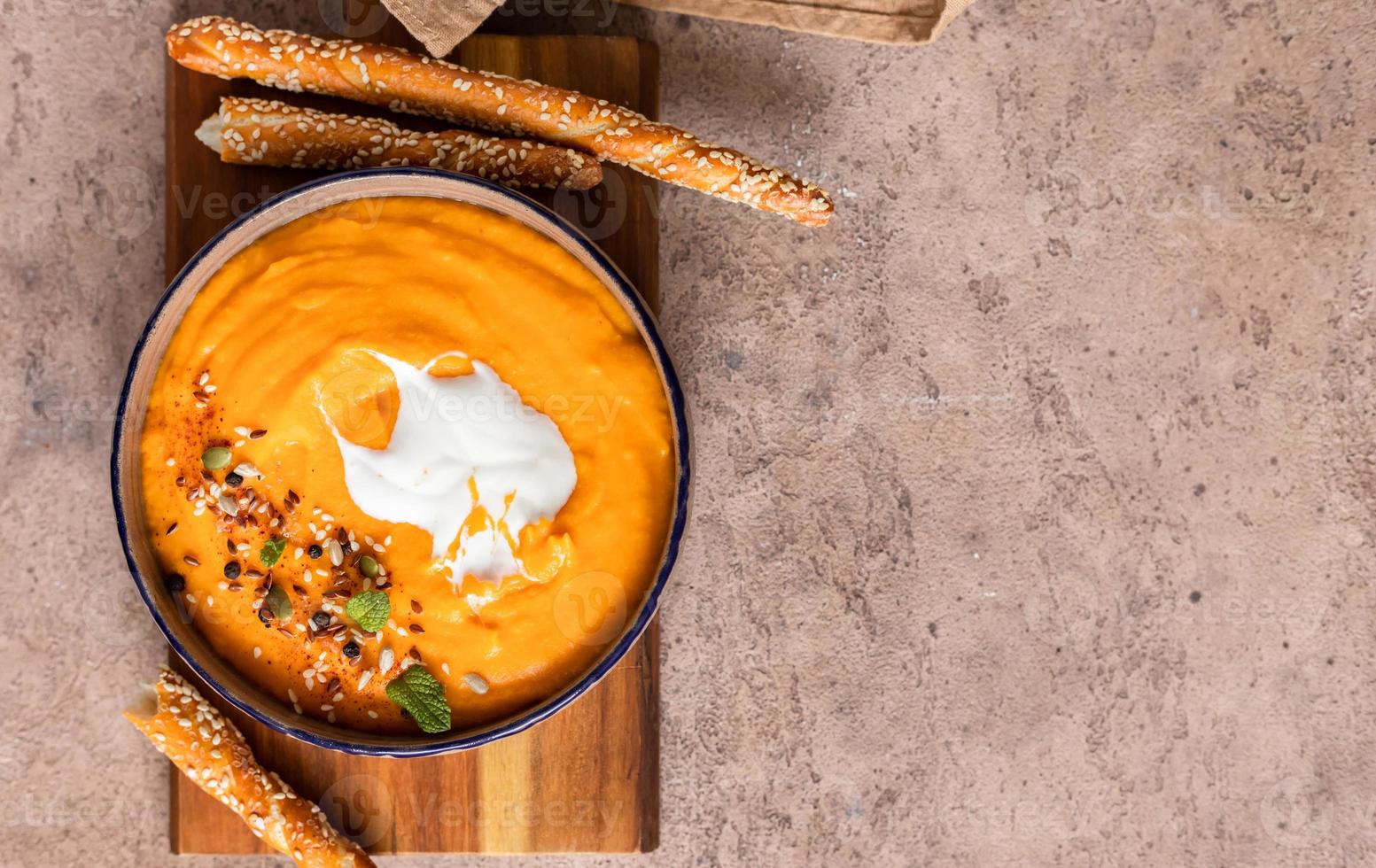 purée de soupe épaisse et soyeuse à base de potiron, carotte et patate douce avec crème, graines et menthe, fond marron. nourriture saine et réconfortante. photo