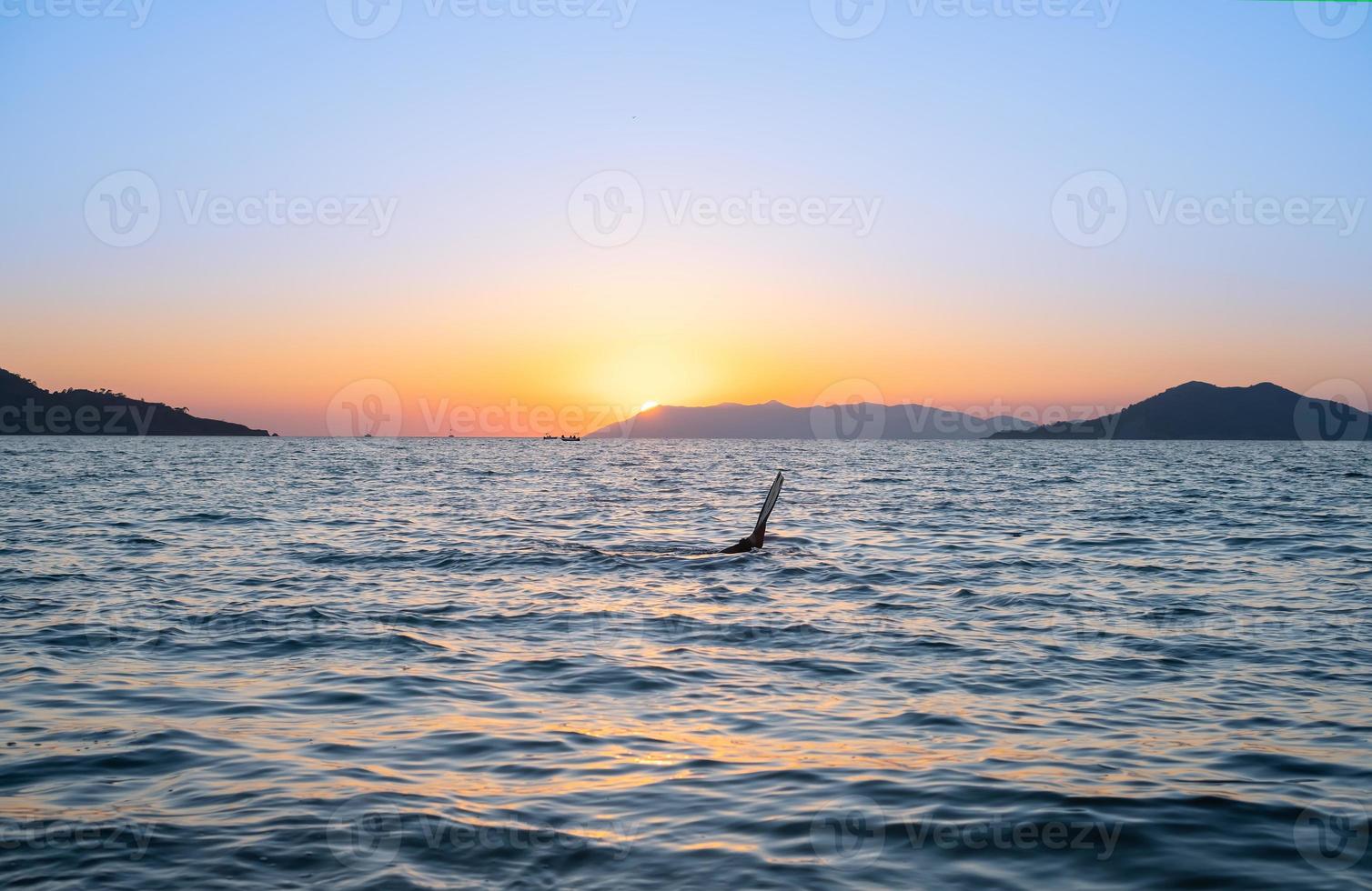 coucher de soleil sur la baie, chasseur de poulpe ou chasseur sous-marin, idée d'économiseur d'écran ou de publicité pour des vacances à la mer photo