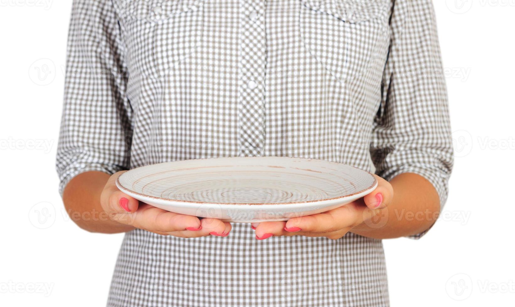 fille dans la chemise à carreaux tient une assiette blanche ronde vide devant elle. la main de la femme tient un plat vide pour vous desing. vue en perspective, isolé sur fond blanc photo