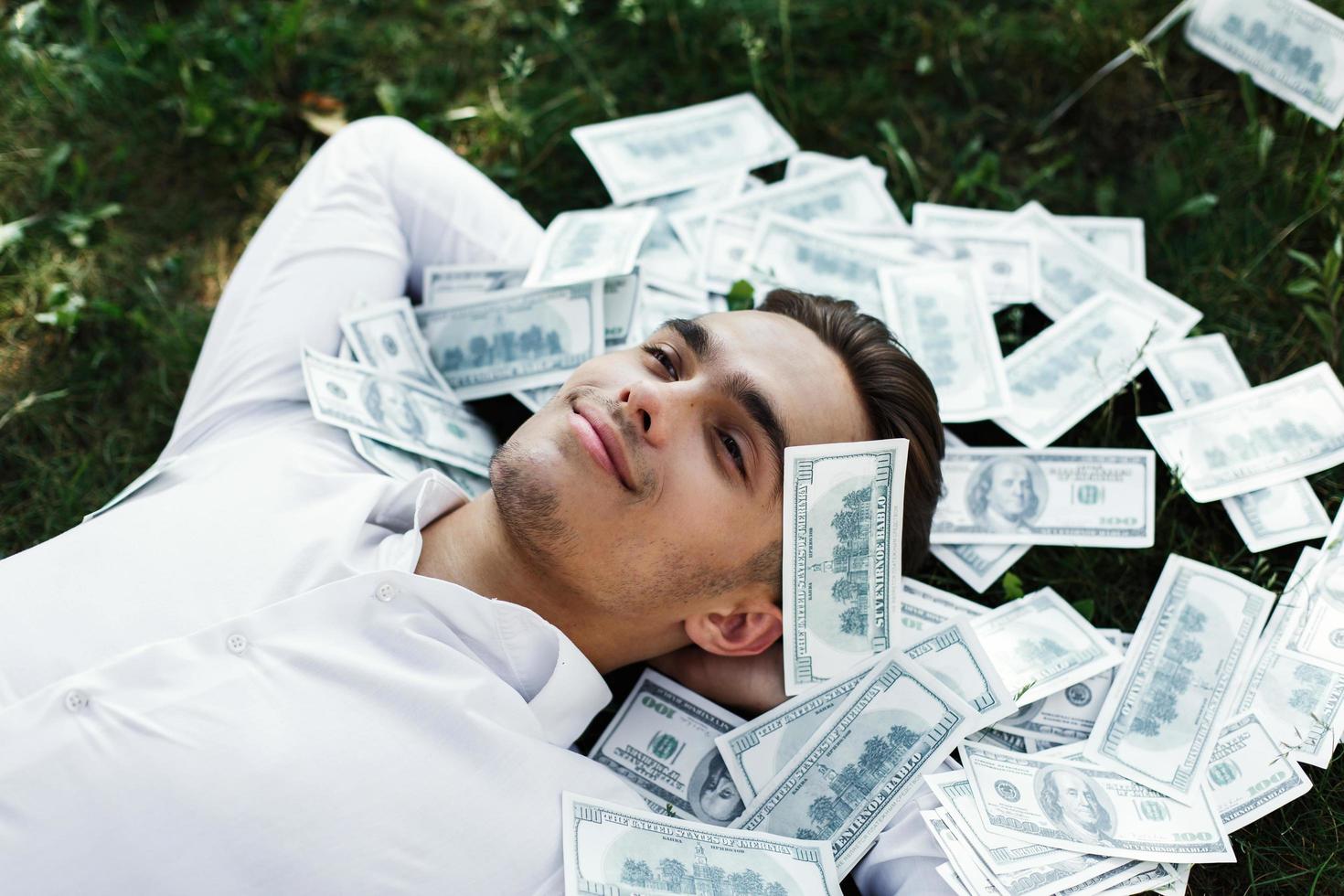 homme couché dans l'herbe avec des billets de cent dollars photo