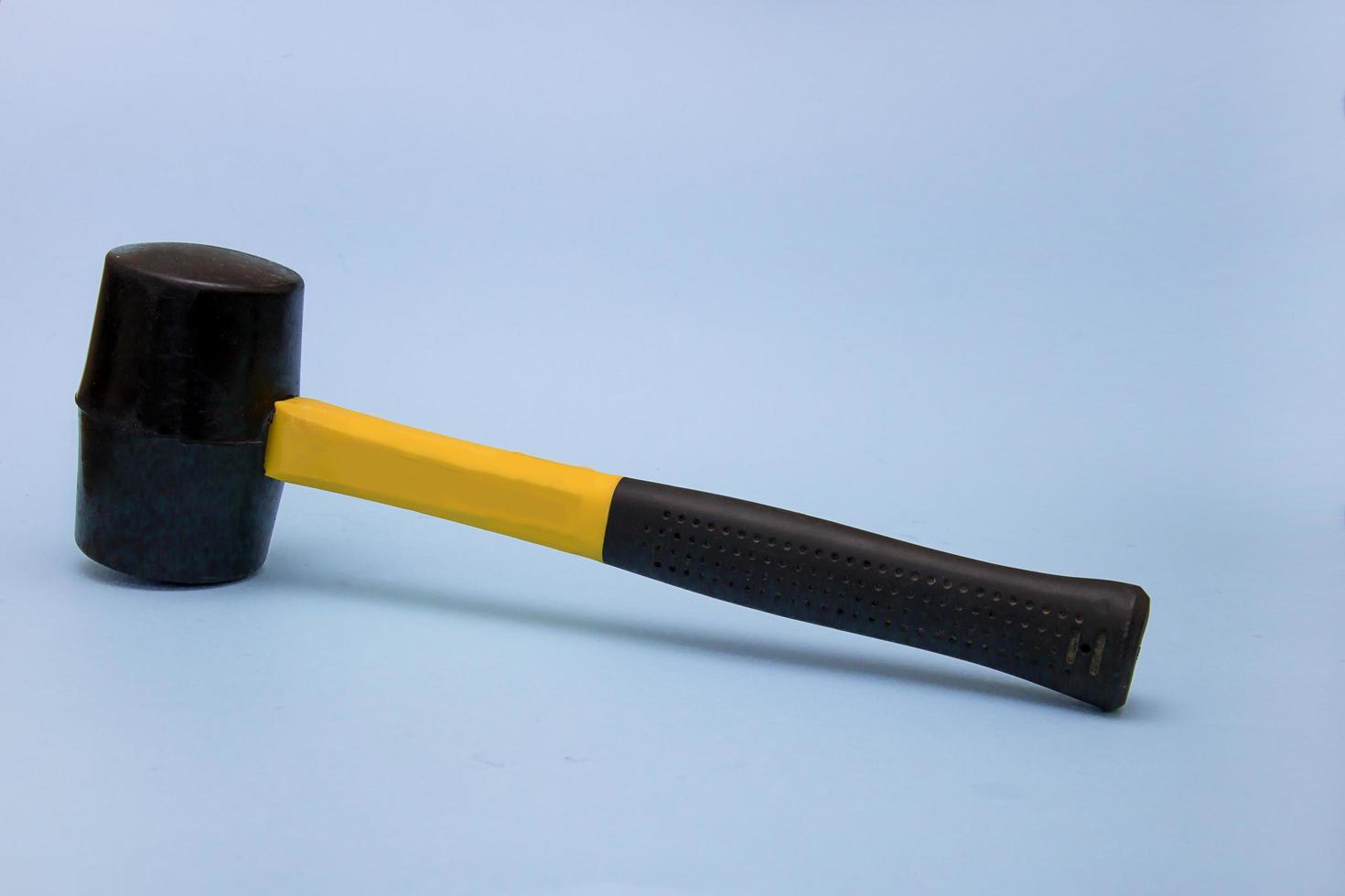 marteau avec une poignée noire et jaune sur fond bleu clair, le concept de construction, d'outils, de réparation, de brutalité photo