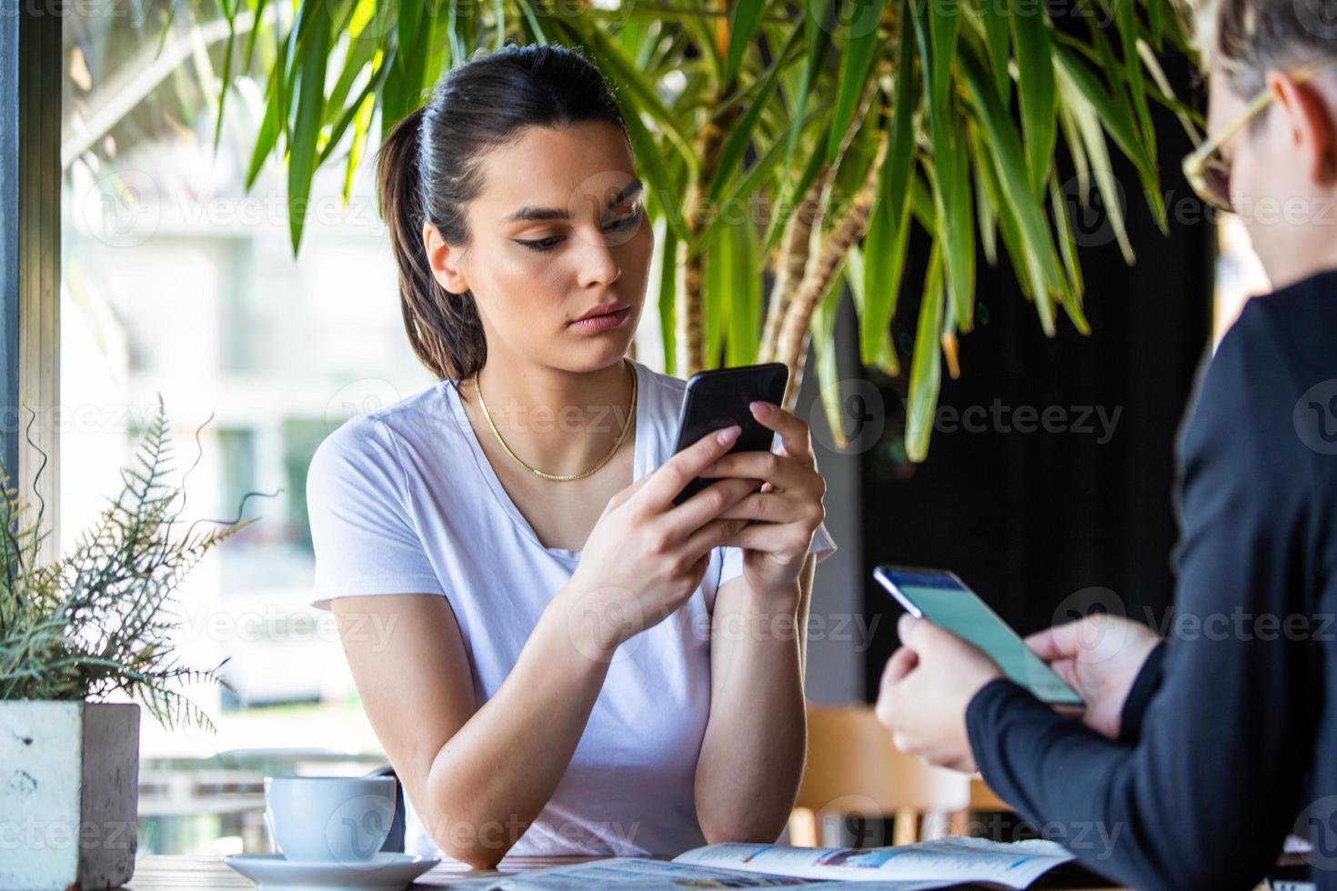 concept de dépendance mobile, amis s'ignorant à l'aide de smartphones se relaxant dans un café, obsédés par les nouvelles applications ou les réseaux sociaux, accros au téléphone perdus dans les nouvelles en ligne photo
