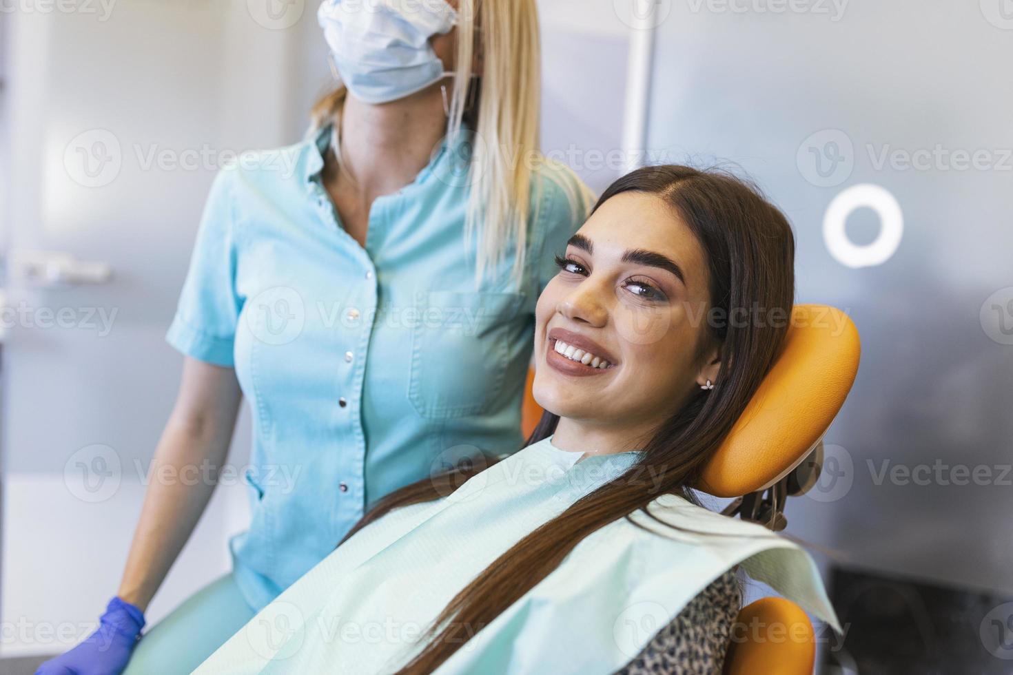 femme brune souriante en cours d'examen par un dentiste à la clinique dentaire. mains d'un médecin tenant des instruments dentaires près de la bouche du patient. concept de dents saines et de médecine photo