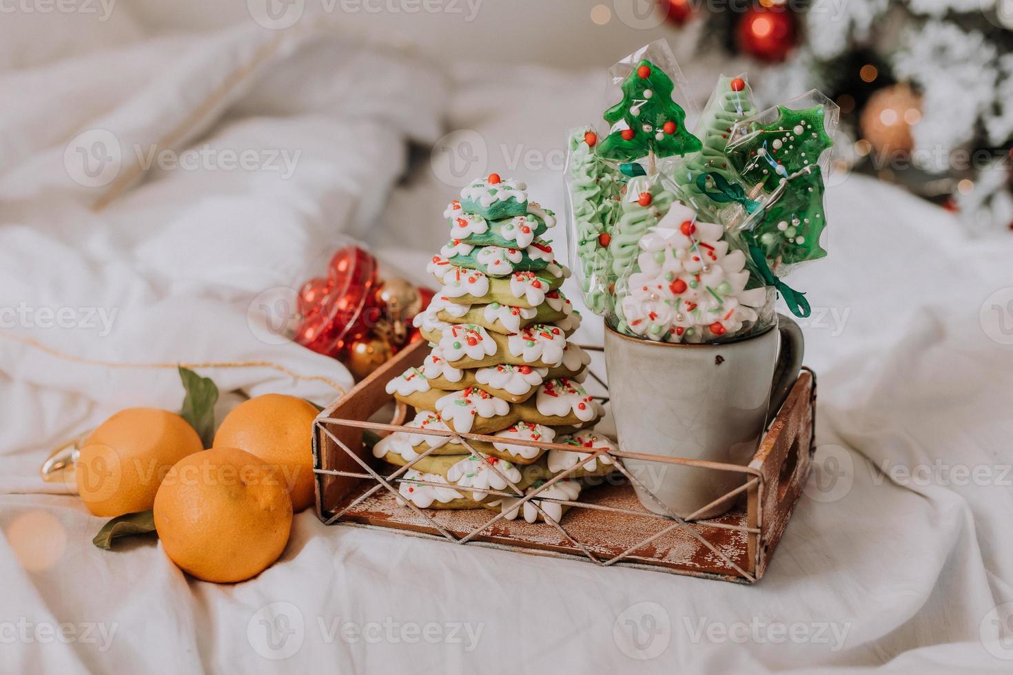 bonbons de noël, pain d'épice peint avec du glaçage, des sucettes et des meringues en forme de sapins de noël et de mandarines sur un beau plateau. gâteaux faits maison. nourriture délicieuse pour les vacances d'hiver photo