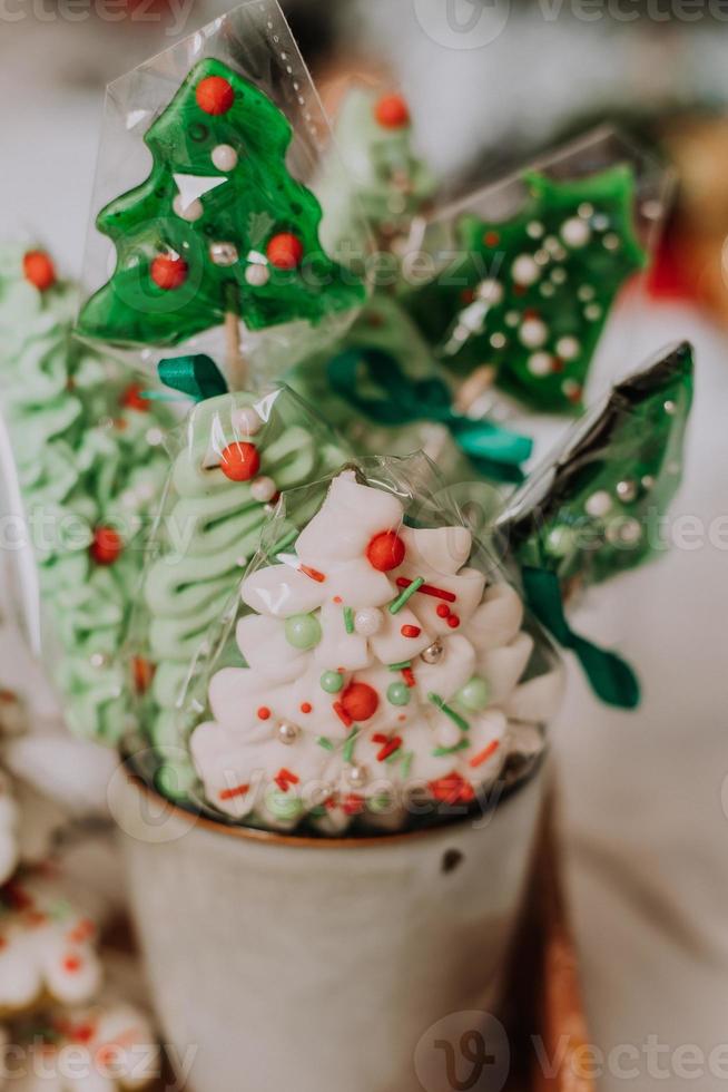 bonbons de noël, pain d'épice peint avec du glaçage, des sucettes et des meringues en forme de sapins de noël et de mandarines sur un beau plateau. gâteaux faits maison. nourriture délicieuse pour les vacances d'hiver photo