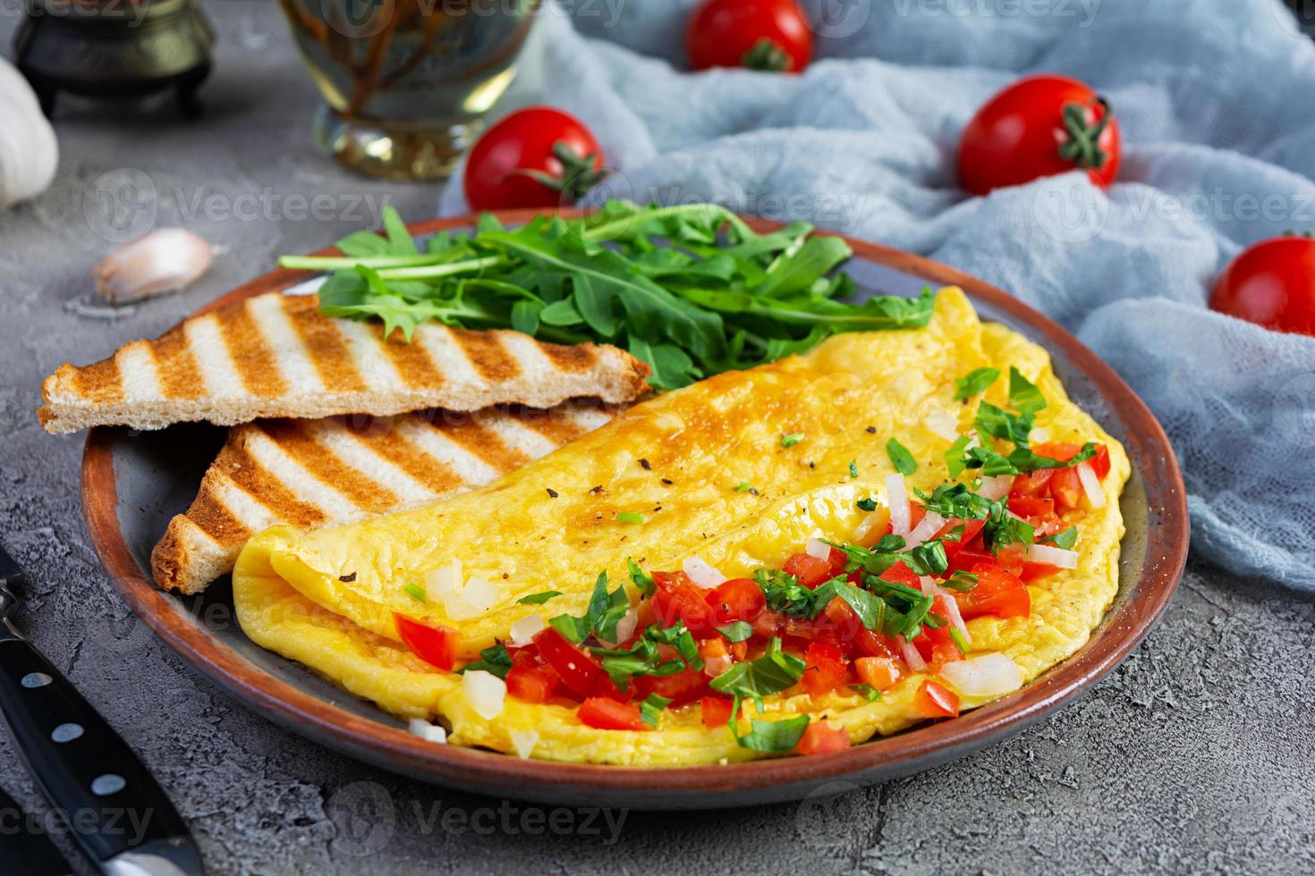 omelette frite aux tomates, oignons et herbes. délicieux petit déjeuner avec des œufs et des toasts photo
