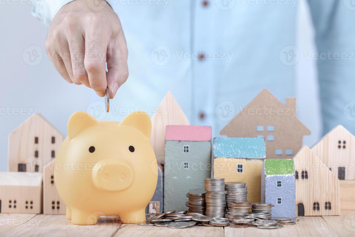 homme d'affaires économiser de l'argent sur la tirelire, planifier l'avenir du loyer pour un concept d'appartement ou de maison. mettre de l'argent à la main dans la tirelire pour économiser pour la maison photo