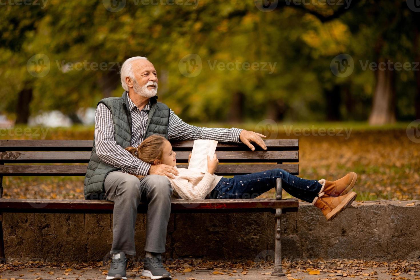 grand-père passe du temps avec sa petite-fille sur un banc dans le parc le jour de l'automne photo