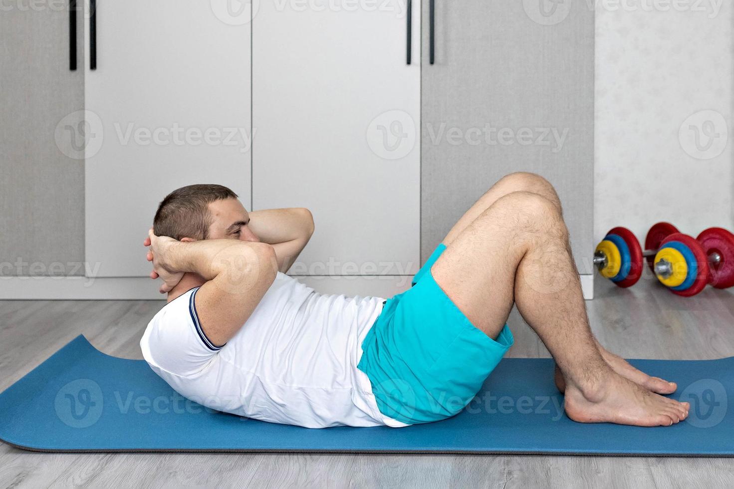 un homme fort et en bonne santé avec des muscles, s'entraînant à la maison. exercices pour les muscles de la presse photo