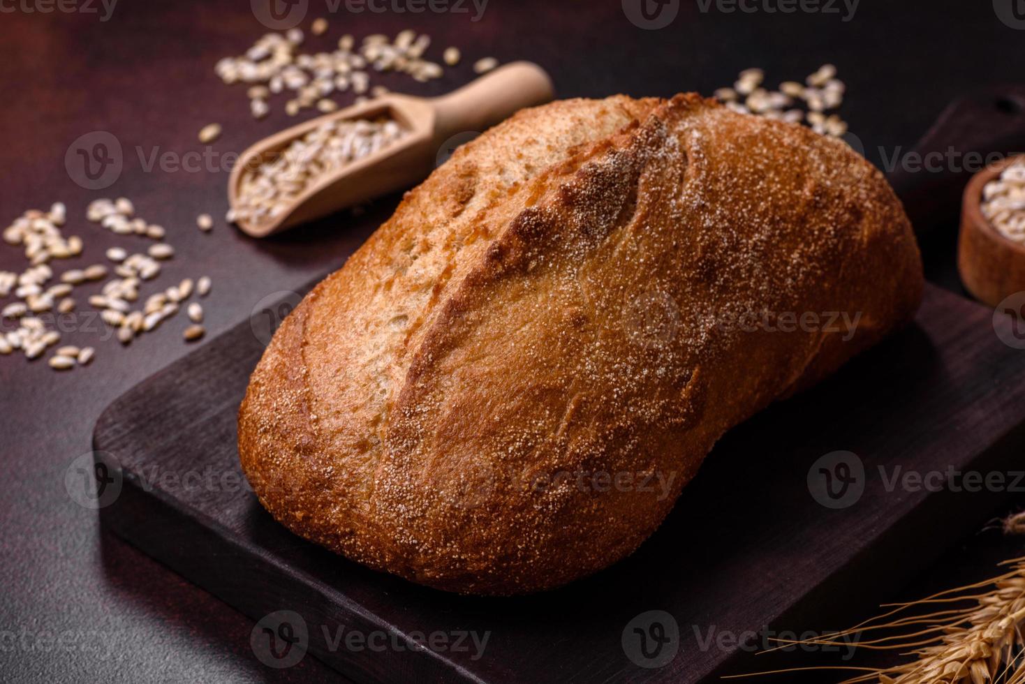 une miche de pain brun avec des grains de céréales sur une planche à découper en bois photo