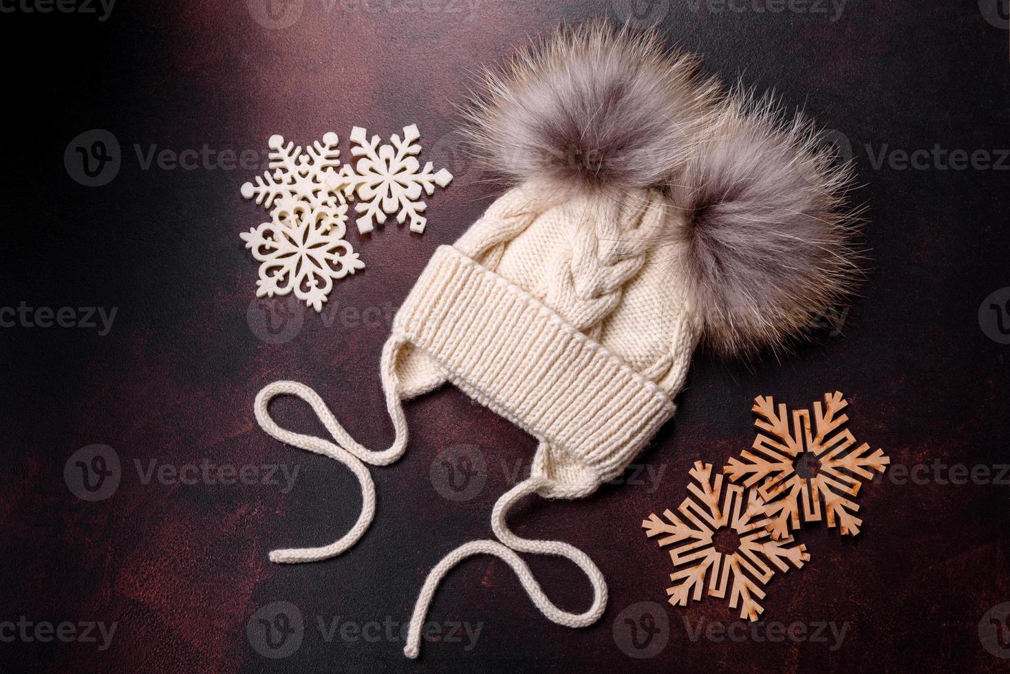 beau bonnet d'hiver tricoté blanc avec pompons sur fond de béton foncé photo