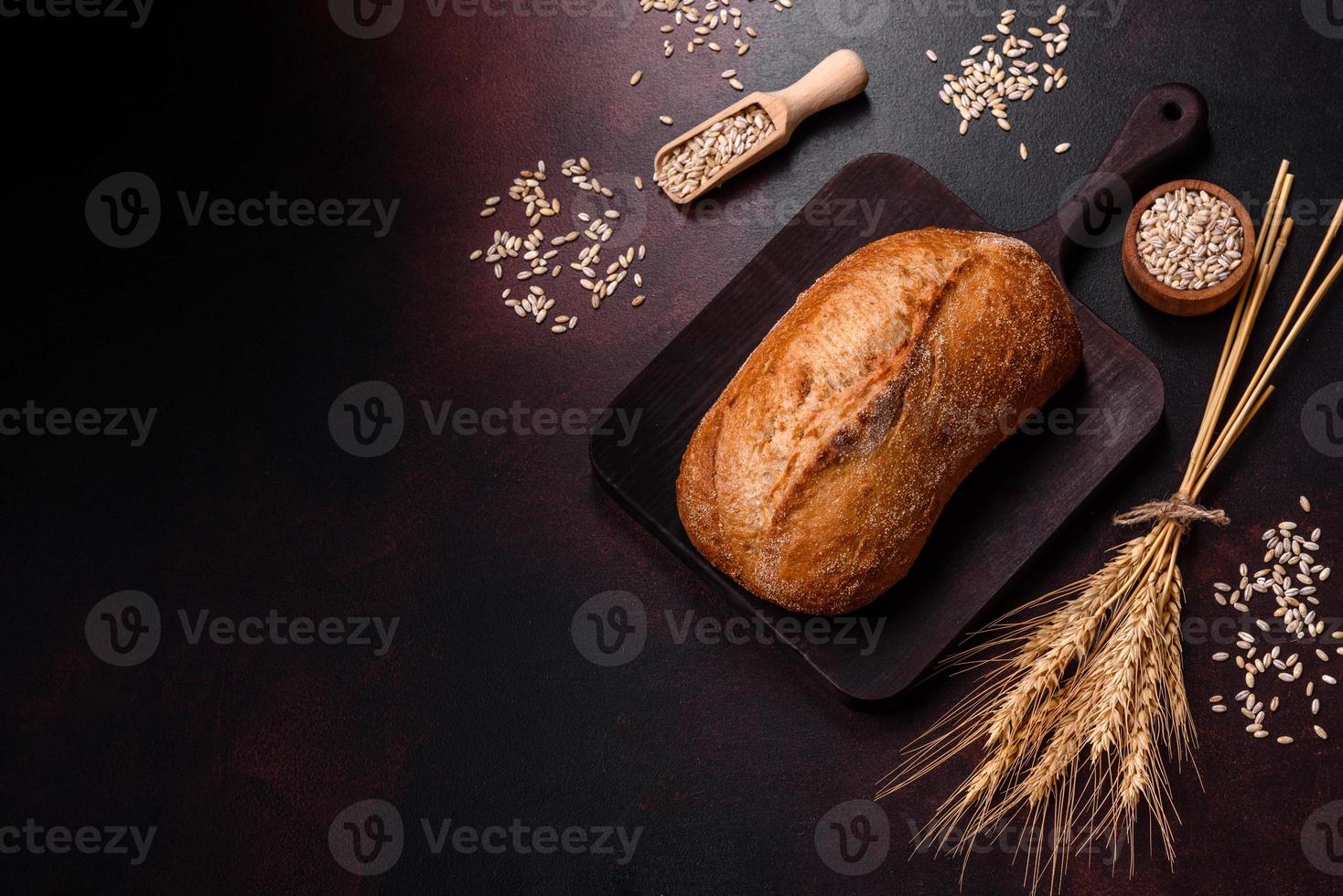 une miche de pain brun avec des grains de céréales sur une planche à découper en bois photo