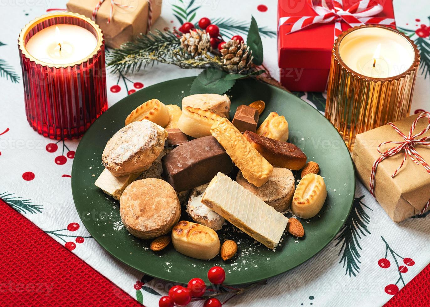 vue de dessus du nougat de noël sucré, des mantecados et des polvorones avec des ornements de noël sur une assiette. assortiment de bonbons de noël typiques d'espagne photo