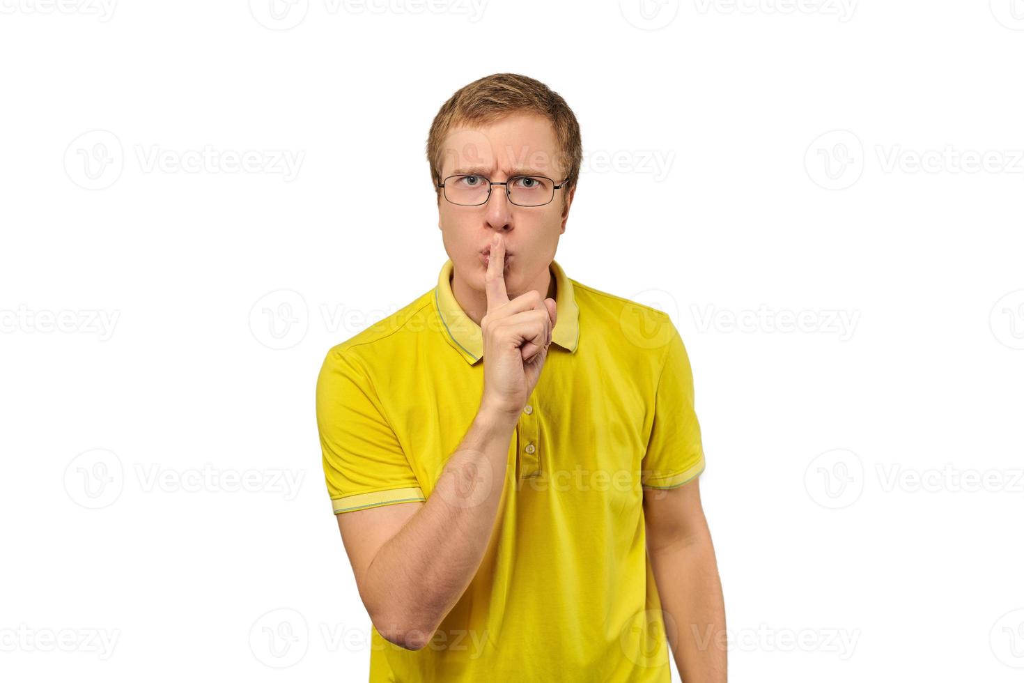 drôle de jeune homme en t-shirt jaune demandant de se taire, geste de silence, fond blanc photo